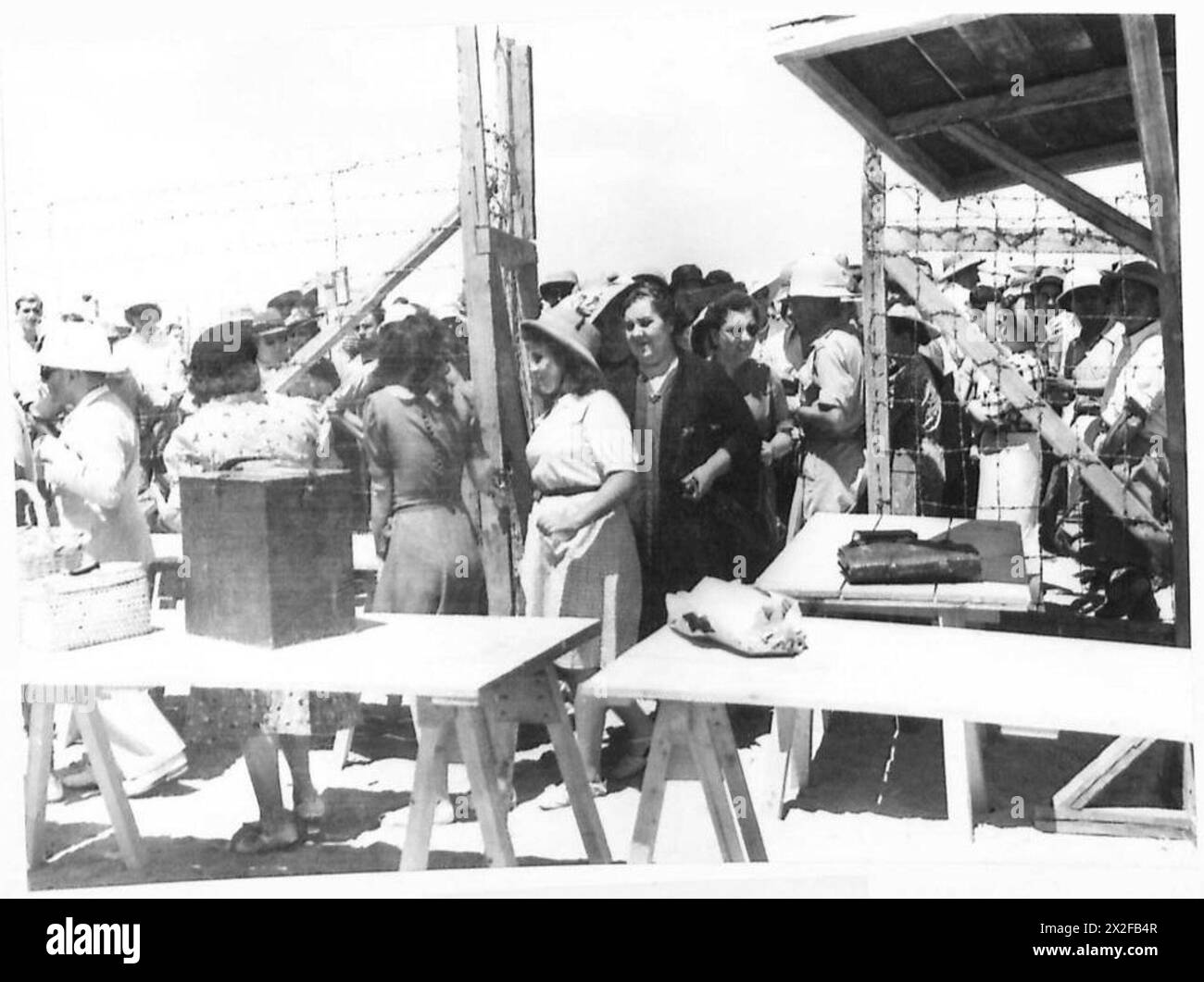 I visitatori arrivano in un campo di internati italiani sotto la supervisione dell'esercito britannico durante la seconda guerra mondiale. L'immagine mostra i civili che entrano nel complesso recintato per la giornata di visita, evidenziando l'ambiente controllato e le misure di sicurezza in tempo di guerra. Foto Stock