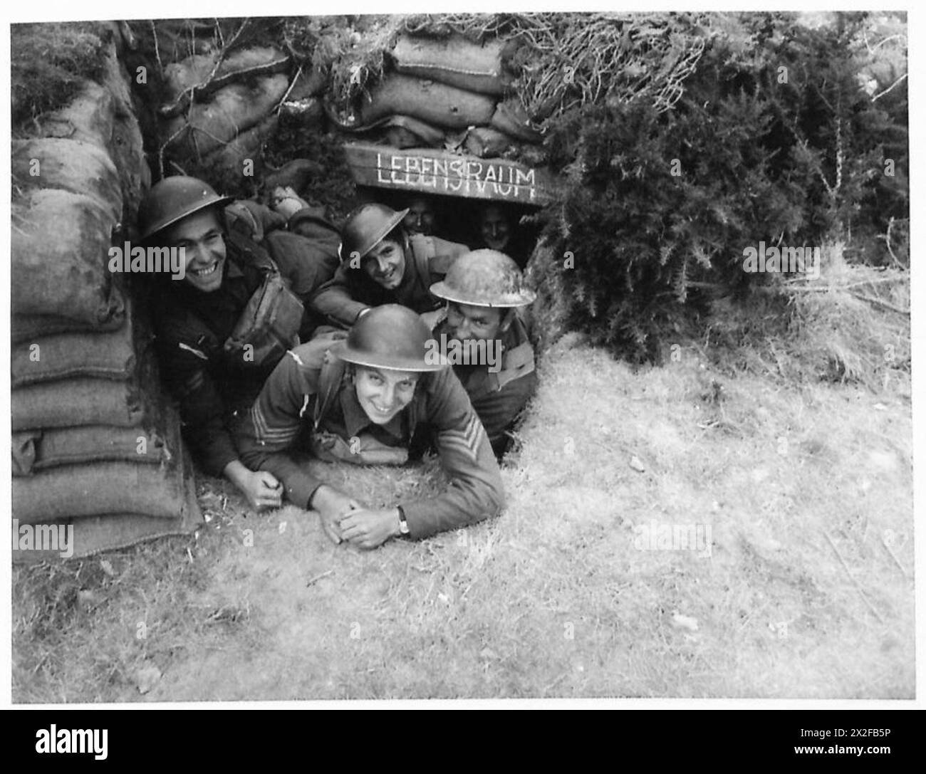 I soldati britannici posano con le armi tedesche catturate in un'area scavata, pronti per il ridispiegamento contro le ex forze nemiche. Foto Stock