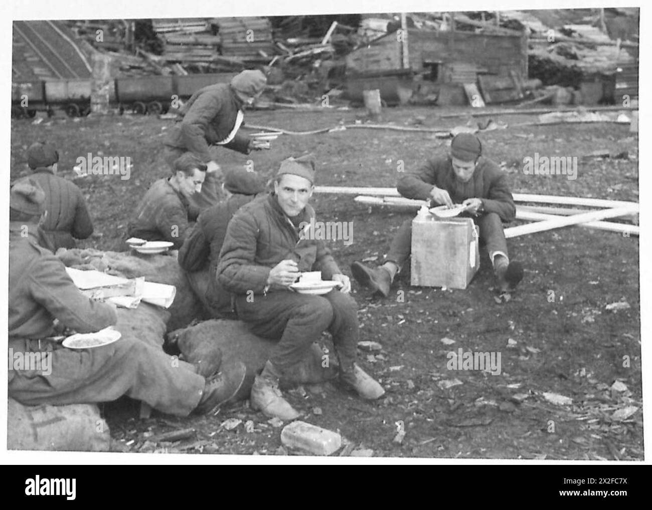Un gruppo di lavoro francese libero, che indossa abiti imbottiti russi, prende un pasto veloce su una spiaggia durante le operazioni dell'esercito britannico nel raid di Spitzbergen. Foto Stock
