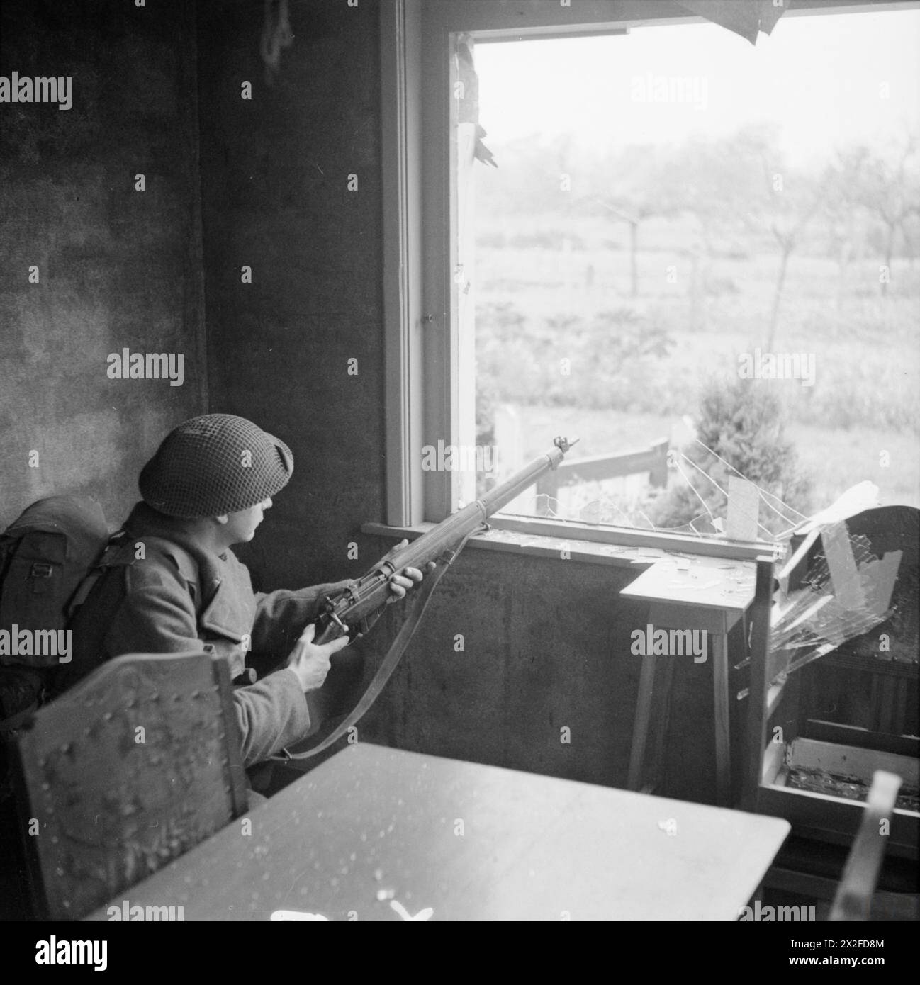 Un 1/5th Queens Regiment fanteria accovacciato in una finestra della casa durante l'attacco a Berlicum, parte dell'avanzata su Hertogenbosch, il 24 ottobre 1944. Foto Stock