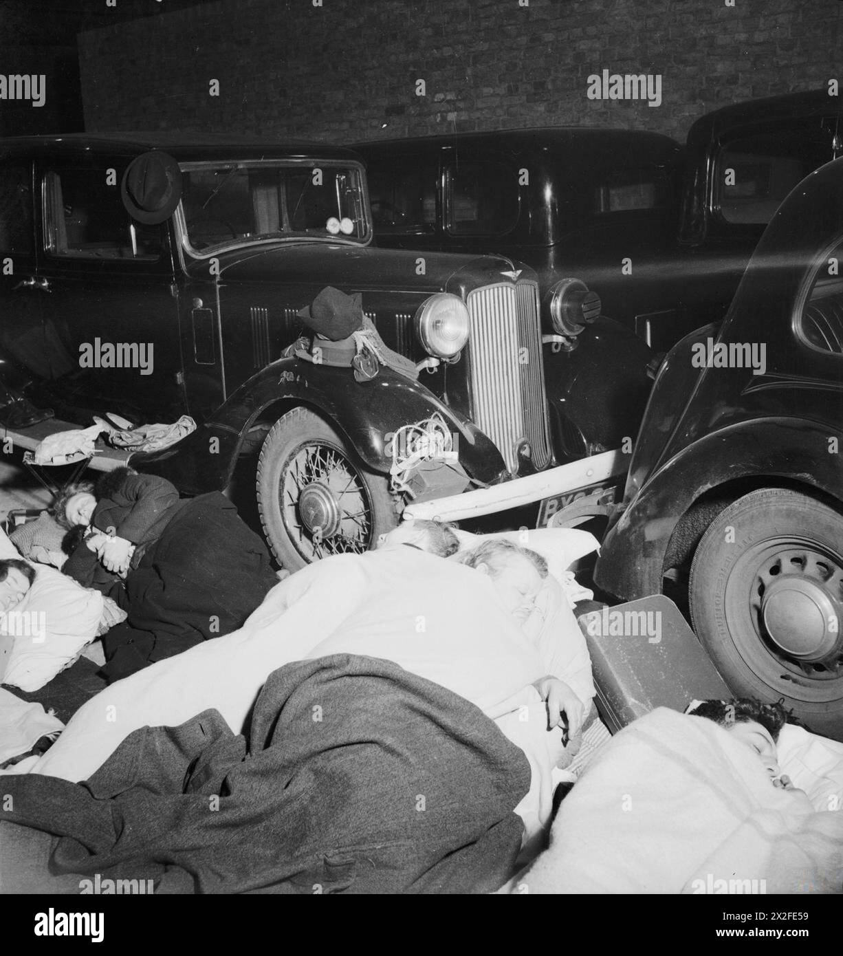 Le persone dormono per la notte in un garage nel sud-ovest di Londra a Pimlico accanto alle auto parcheggiate, fotografato in bianco e nero da Bill Brandt nel novembre 1940. Foto Stock