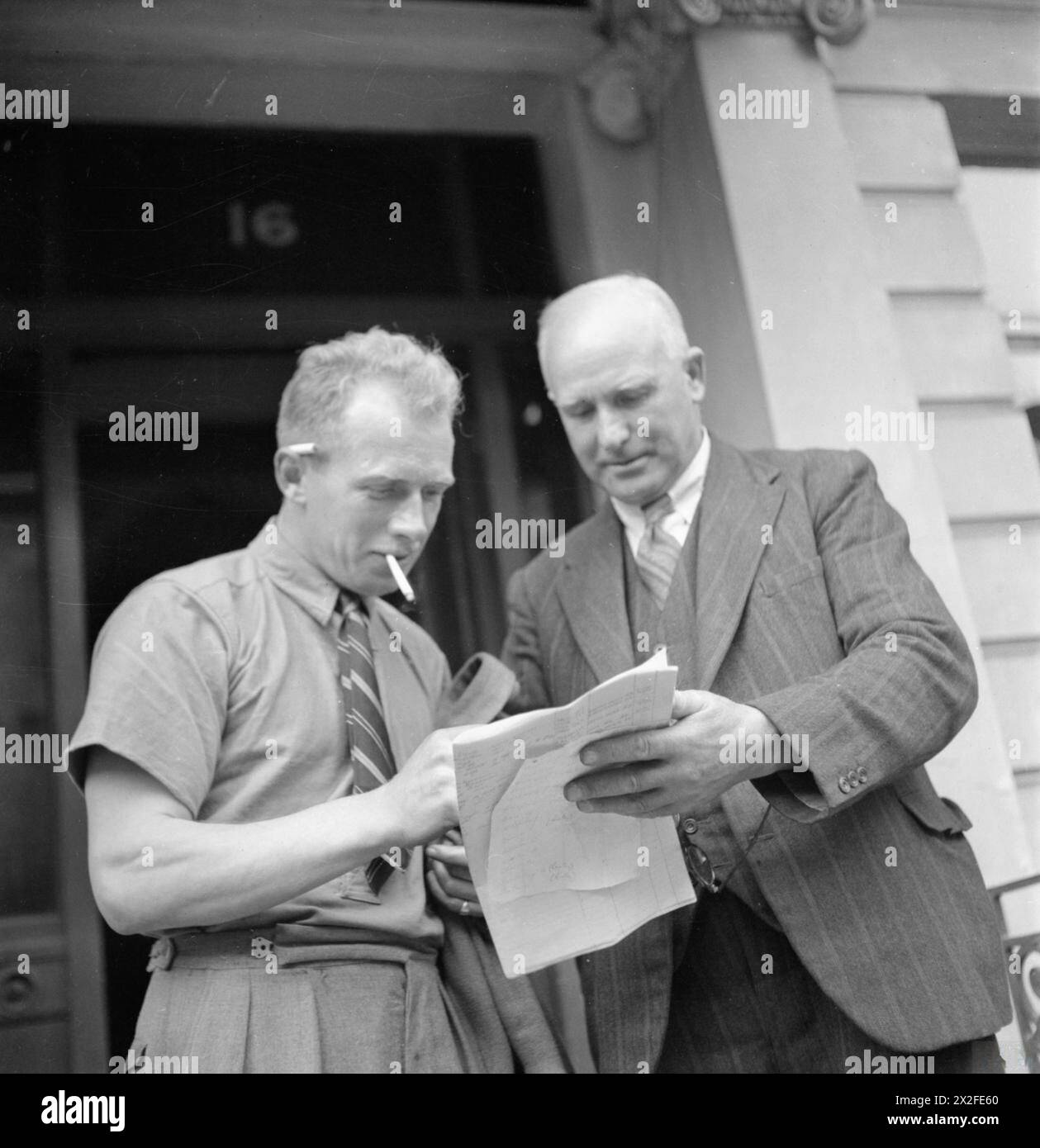 BLITZ REPAIR SQUAD'S LONDON CAMP: EVERYDAY LIFE WITH THE BLITZ REPAIR TEAMS, LONDON, ENGLAND, UK, 1944 - Foreman J Wigley (di Darlington) discute il suo lavoro quotidiano con il suo capo, l'appaltatore C Dougill, (di Dougill and Sons Ltd, Darlington) fuori dal suo billet al 16 di Onslow Square, Londra. Il signor Wigley fa parte della "Blitz Repair Squad", una squadra di costruttori che sono venuti a Londra da varie parti del paese per aiutare a riparare i danni causati dalle bombe volanti V1 Foto Stock