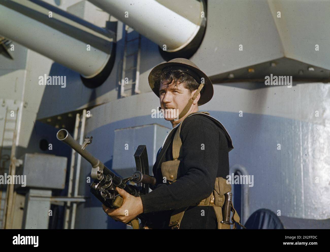 Nel novembre 1942, un marinaio della Royal Navy a bordo di una nave da battaglia indossa un casco d'acciaio e trasporta un cannone Bren durante le operazioni in mare. Foto Stock