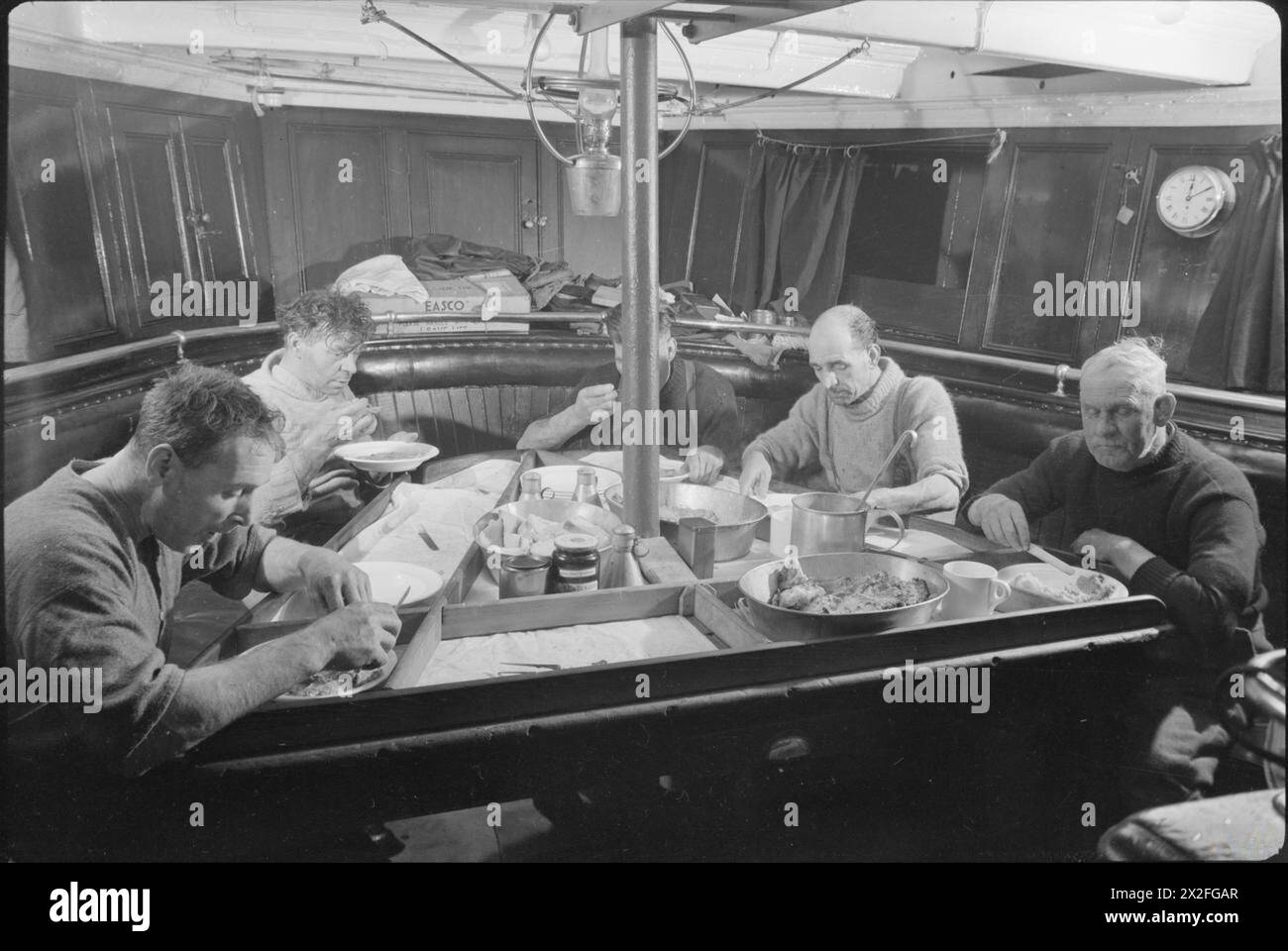 L'equipaggio della SS Righto, un peschereccio del Mare del Nord con base a Grimsby, pranza nella sala del reparto nel 1945. I pasti sono serviti in due turni: Colazione alle 7:30, pranzo alle 12:00, tè alle 18:30. L'equipaggio include lo skipper George Burgess, il secondo ingegnere George Wallsworth, Mate W J Harwood e il terzo uomo J W Barber. Foto Stock