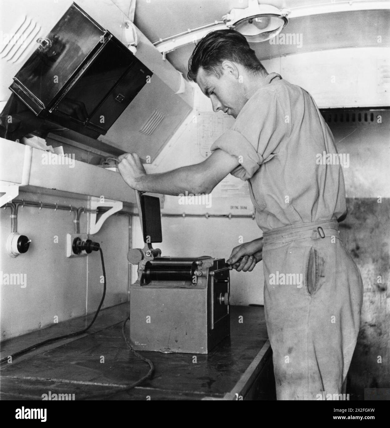 Un assistente fotografico ha sviluppato una pellicola di ricognizione aerea attraverso una stampante a contatto in un rimorchio fotografico in un terreno di atterraggio egiziano durante le operazioni RAF, 1939-1943. Foto Stock