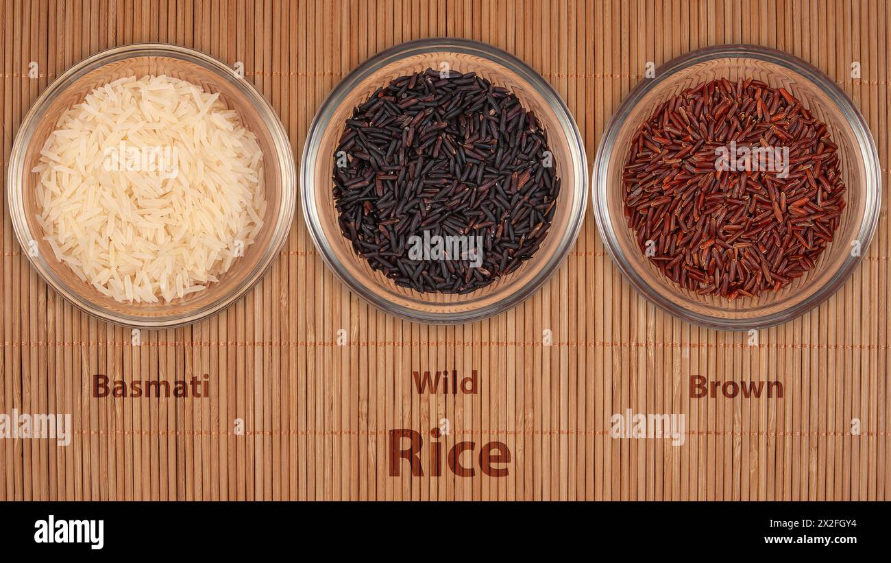 Tre ciotole trasparenti mostrano diverse varietà di riso: Basmati, Wild e Brown. L'assortimento rappresenta diversi tipi di cereali utilizzati in cu internazionale Foto Stock