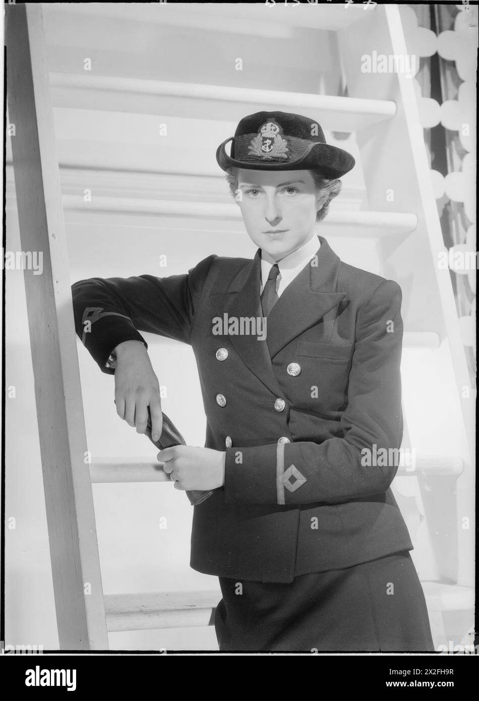 Un ufficiale del Women's Royal Naval Service indossa un'uniforme blu navy con insegne di rango sulle maniche e un cappello tricorne nero con alloro, corona e distintivo di ancora, fotografato in una stampa della mostra Cecil Beaton degli anni '1940. Foto Stock
