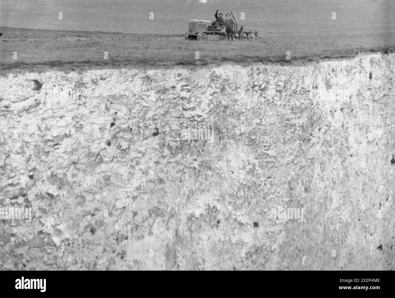 L'agricoltore Gilbert Mitchell e l'autista di trattori C. Rogers lavorano nei campi lungo le White Cliffs di dover, Kent, Inghilterra, c. 1944, osservando gli aerei in testa mentre svolgevano attività agricole quotidiane. Foto Stock