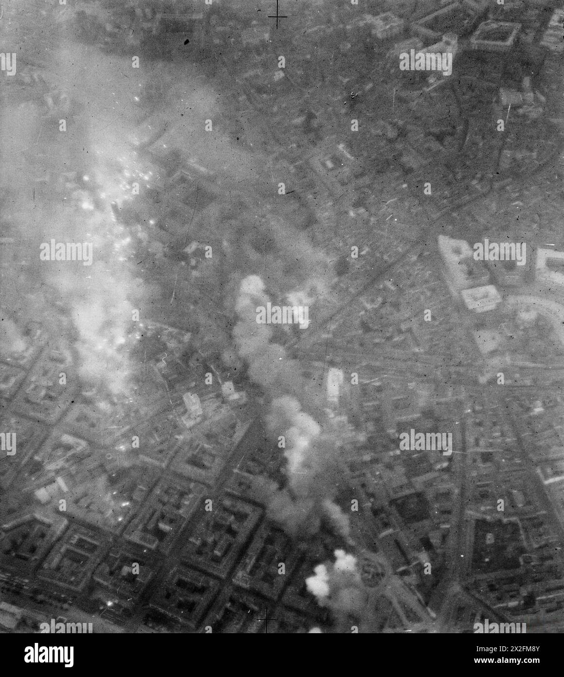 Una fotografia aerea verticale mostra il fumo che sale da 30 libbre di bombe incendiarie sganciate da 88 bombardieri Avro Lancaster del No. 5 Group RAF durante un raid alla luce del giorno su Milano, Italia, tra il 1942 e il 1945. Foto Stock