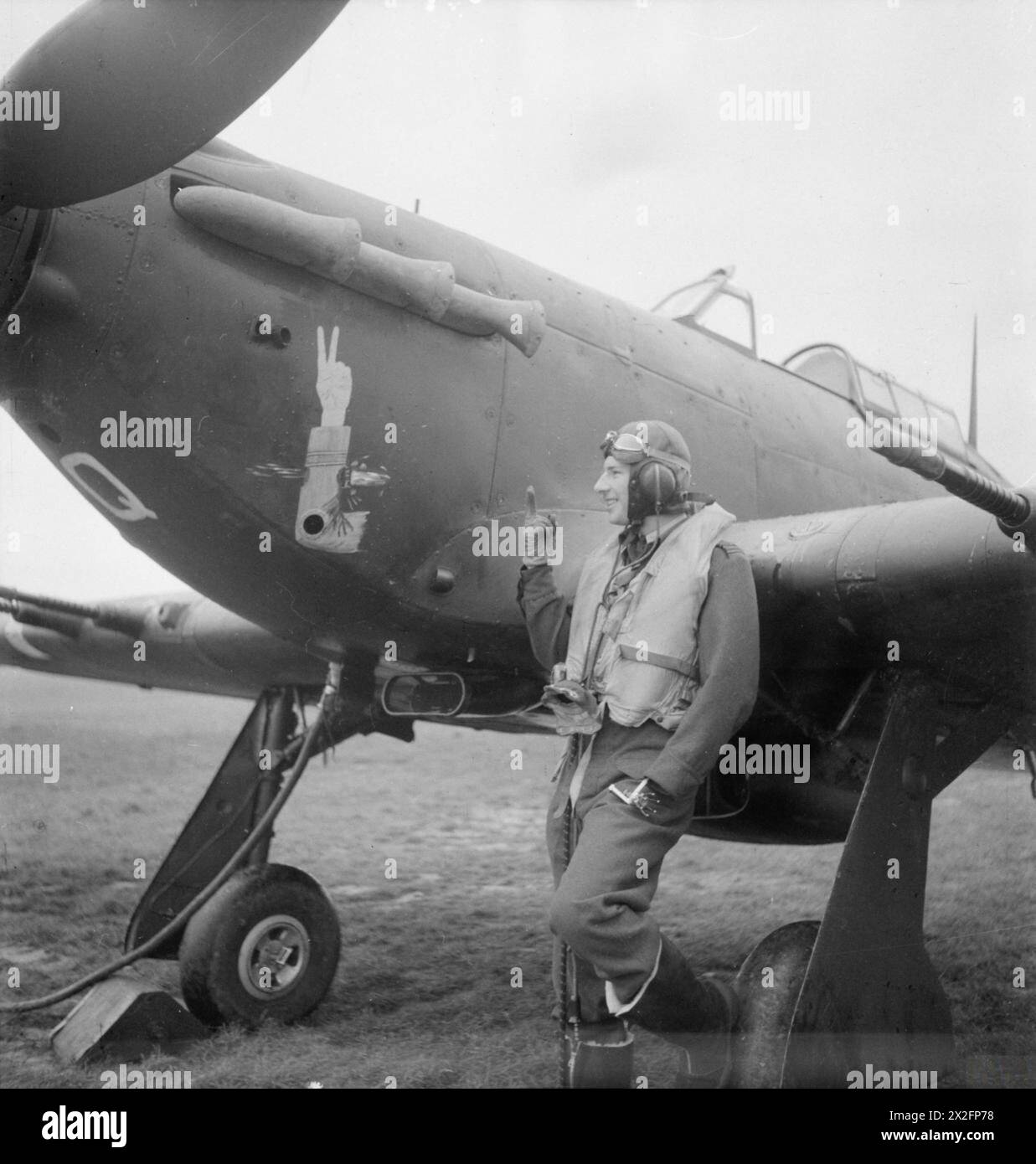 ROYAL AIR FORCE FIGHTER COMMAND, 1939-1945. - Il capo di squadra J A F MacLachlan, l'ufficiale comandante del No 1 Squadron RAF, accanto al suo caccia notturno Hawker Hurricane Mark IIC, 'JX-Q', a Tangmere, Sussex. MacLachlan volò bombardieri in Francia nel 1940, ma fu trasferito ai caccia nel giugno 1940 e abbatté 6 aerei nemici durante la battaglia d'Inghilterra. Si unì al No. 261 Squadron RAF a Malta, come comandante di volo, e fu abbattuto nel febbraio 1941, a causa del quale il suo braccio sinistro fu amputato. Tornò rapidamente alle operazioni dopo essere stato dotato di un artificiale Foto Stock