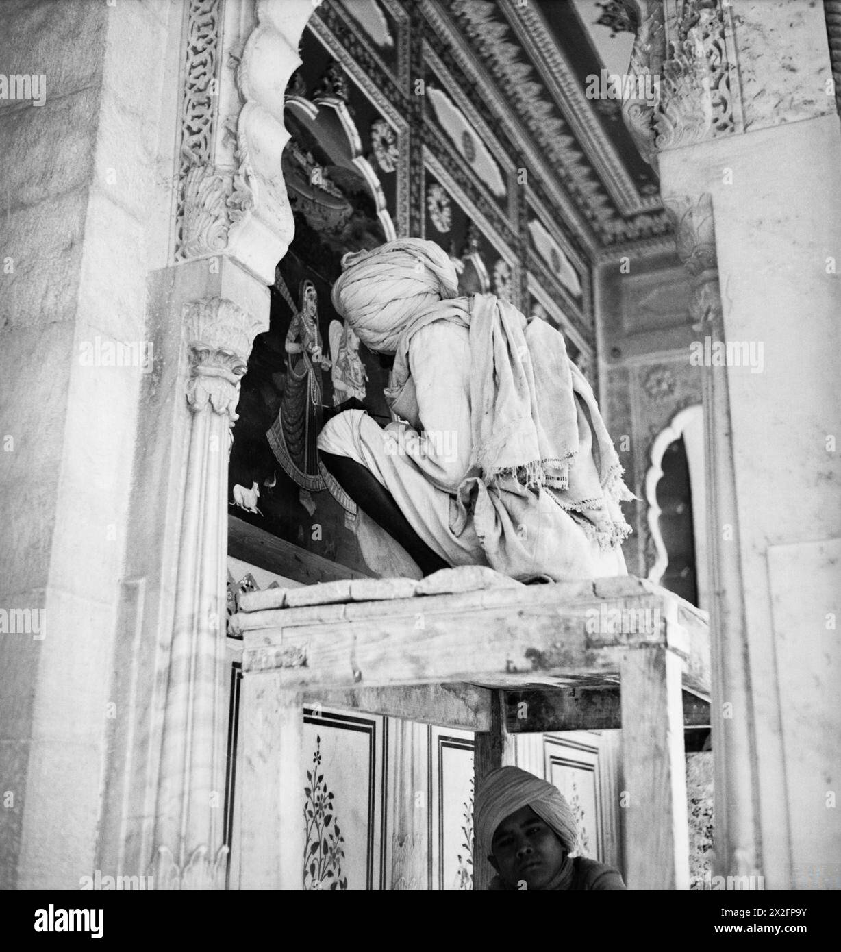 Un operaio rinnova i dipinti all'ingresso dei quartieri del Maharanee nel City Palace di Jaipur, India centrale. Foto Stock