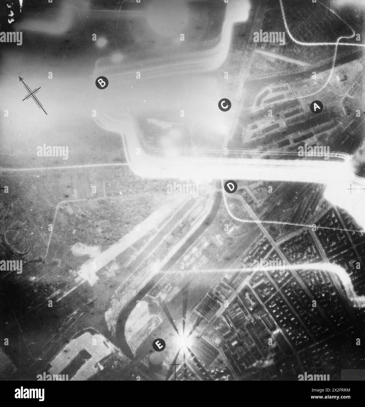 LE INCURSIONI AEREE della RAF CONTRO LA GERMANIA, 1940 - annotarono la vista aerea verticale scattata durante un attacco notturno ai moli di Westhafen, Berlino. Nella notte del 7-8 ottobre 1940, 42 aerei dei gruppi 3 e 4 bombardarono 12 bersagli individuali nella capitale tedesca per la perdita di un Vickers Wellington. Le ampie strisce di luce sono proiettori tedeschi, quelli sottili sono gusci traccianti. I moli sono chiaramente visibili ("A'), illuminati dall'esplosione di una bomba sul porto interno del canale navale di Spandau ("C"). Altre caratteristiche scelte includono il ponte Koenigs Damm sul canale Verbindunge ('D') A. Foto Stock