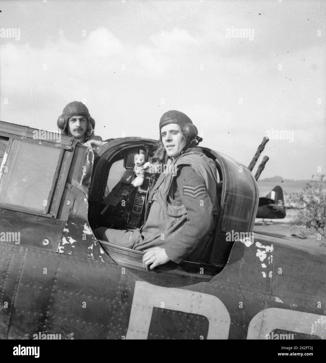 ROYAL AIR FORCE FIGHTER COMMAND, 1939-1945. - Il sergente di volo e R Thorn (pilota a sinistra) e il sergente F J Barker (cannoniere) del No 264 Squadron RAF e la loro mascotte Teddy Bear, presentati loro dal loro equipaggio di terra, in posa con il loro Boulton-Paul Defiant Mark i a Biggin Hill, Kent, dopo aver distrutto il loro primo Heinkel He 111, portando il loro totale di aerei nemici distrutti a tredici. Questi due sergenti divennero il più riuscito sodalizio Defiant della guerra Royal Air Force, 264 Squadron Foto Stock