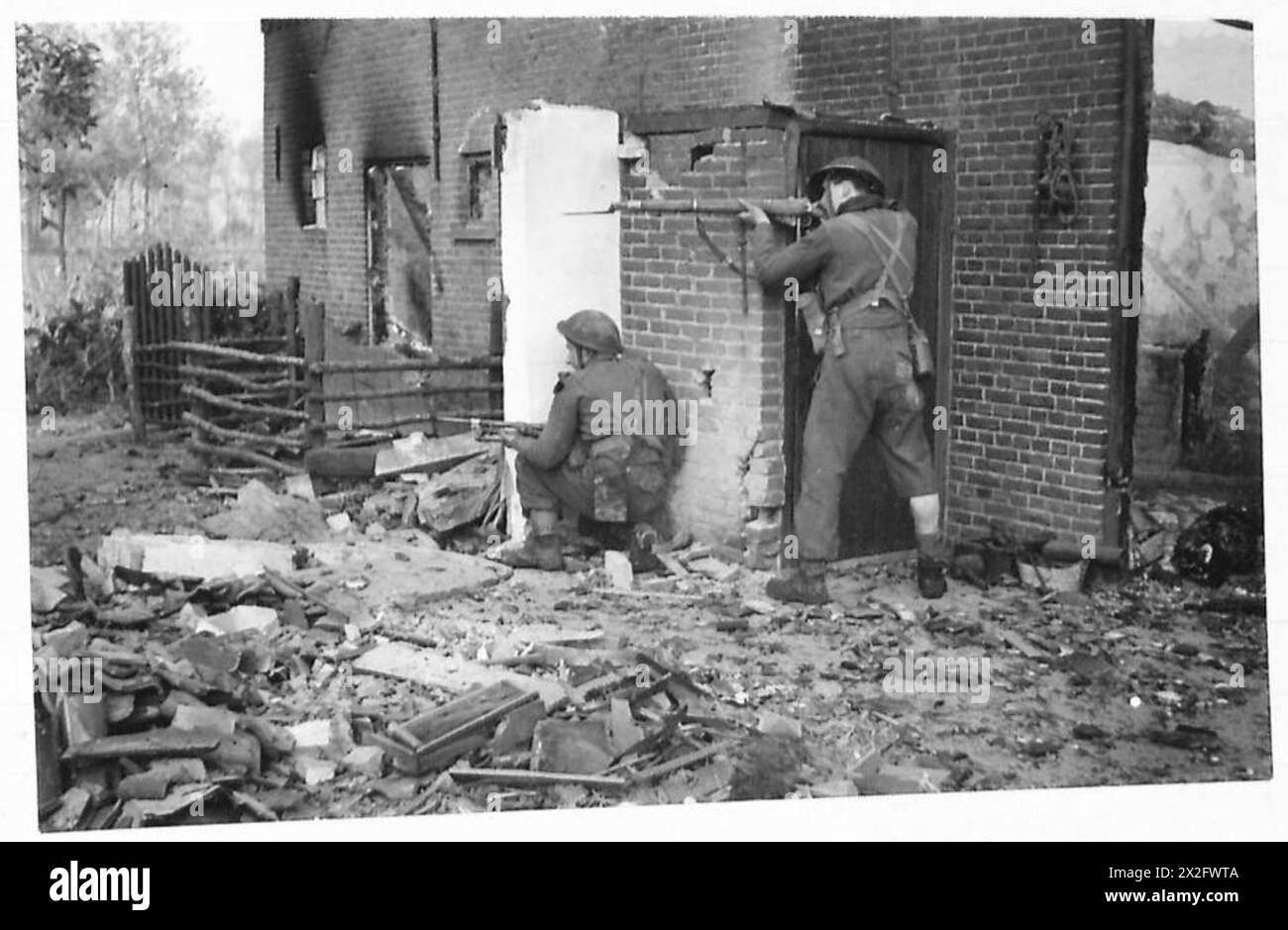 La fanteria del 21st Army Group dell'esercito britannico si impegnò in combattimenti intorno agli edifici in fiamme alla periferia di Bokstal, documentando le condizioni della guerra urbana durante la seconda guerra mondiale Foto Stock