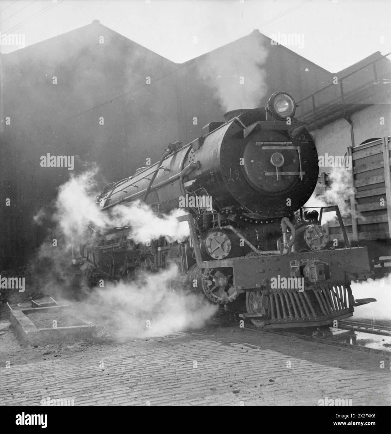 L'INDUSTRIA BRITANNICA DELLA COSTRUZIONE DI LOCOMOTIVE: LA PRODUZIONE DI LOCOMOTIVE FERROVIARIE, Regno Unito, 1945 - Una fotografia impressionante di una locomotiva sudafricana di classe 15F con scartamento 3' 6' che viene sottoposta a un test finale a vapore in un'officina, da qualche parte in Gran Bretagna. In base alla didascalia originale, il motore è di tipo 4-8-2, e pesa 111 tonnellate 12 cwts Foto Stock