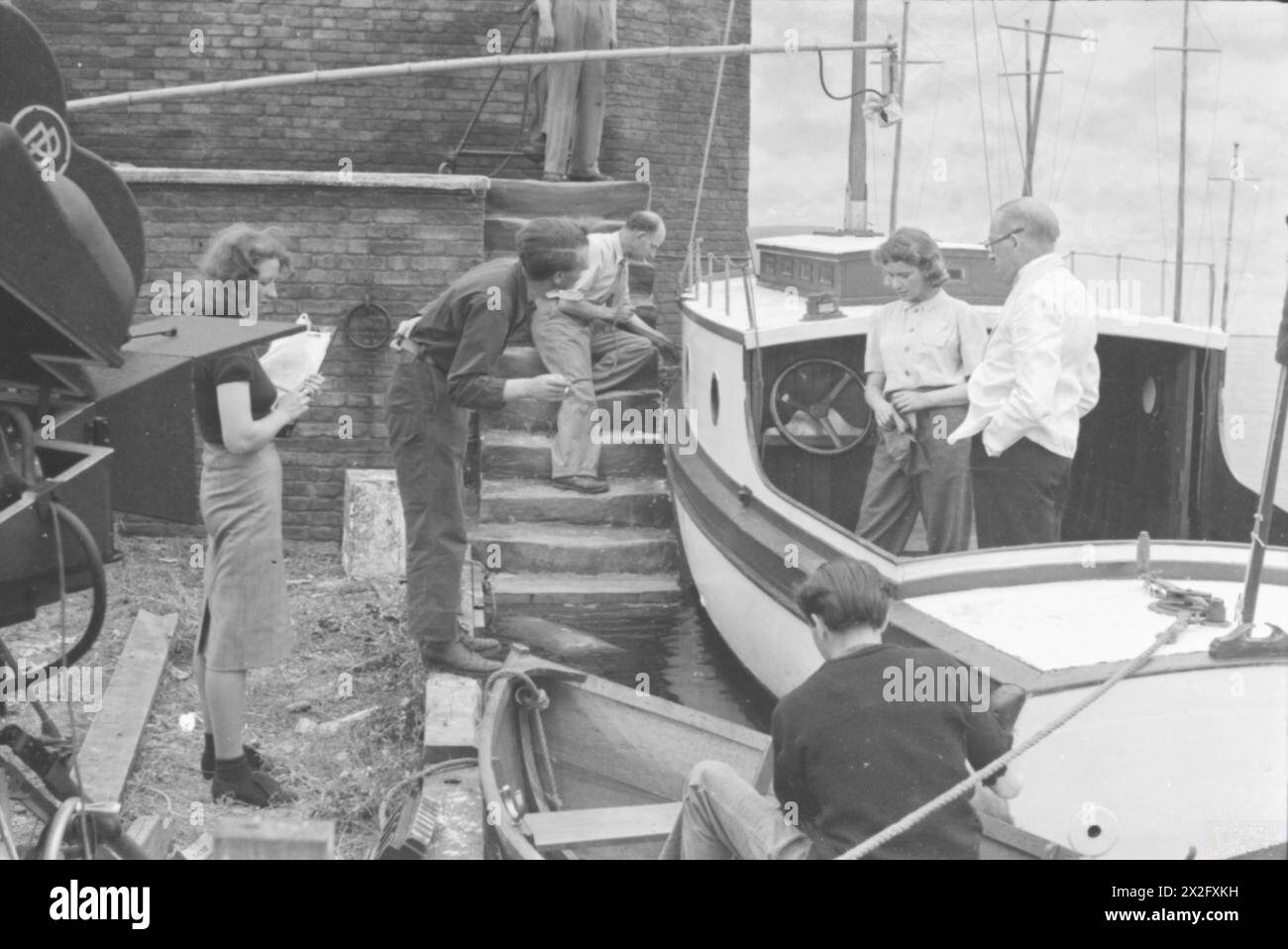 CHANNEL INCIDENT: THE PRODUCTION OF A MINISTRY OF INFORMATION FILM, UK, SETTEMBRE 1940 - Anthony Asquith dirige Peggy Ashcroft e Gordon Harker in "Channel Incident", un film sull'evacuazione di Dunkirk realizzato da Denham e Pinewood Studios per il Ministero dell'informazione nel 1940. Le stelle sono in piedi a bordo di uno yacht a motore, chiamato "Wanderer" nel film. Anche la ragazza della continuità, altri due membri della troupe di produzione e il microfono sono in foto Asquith, Anthony, Ashcroft, Edith Margaret Emily, Harker, Gordon Foto Stock