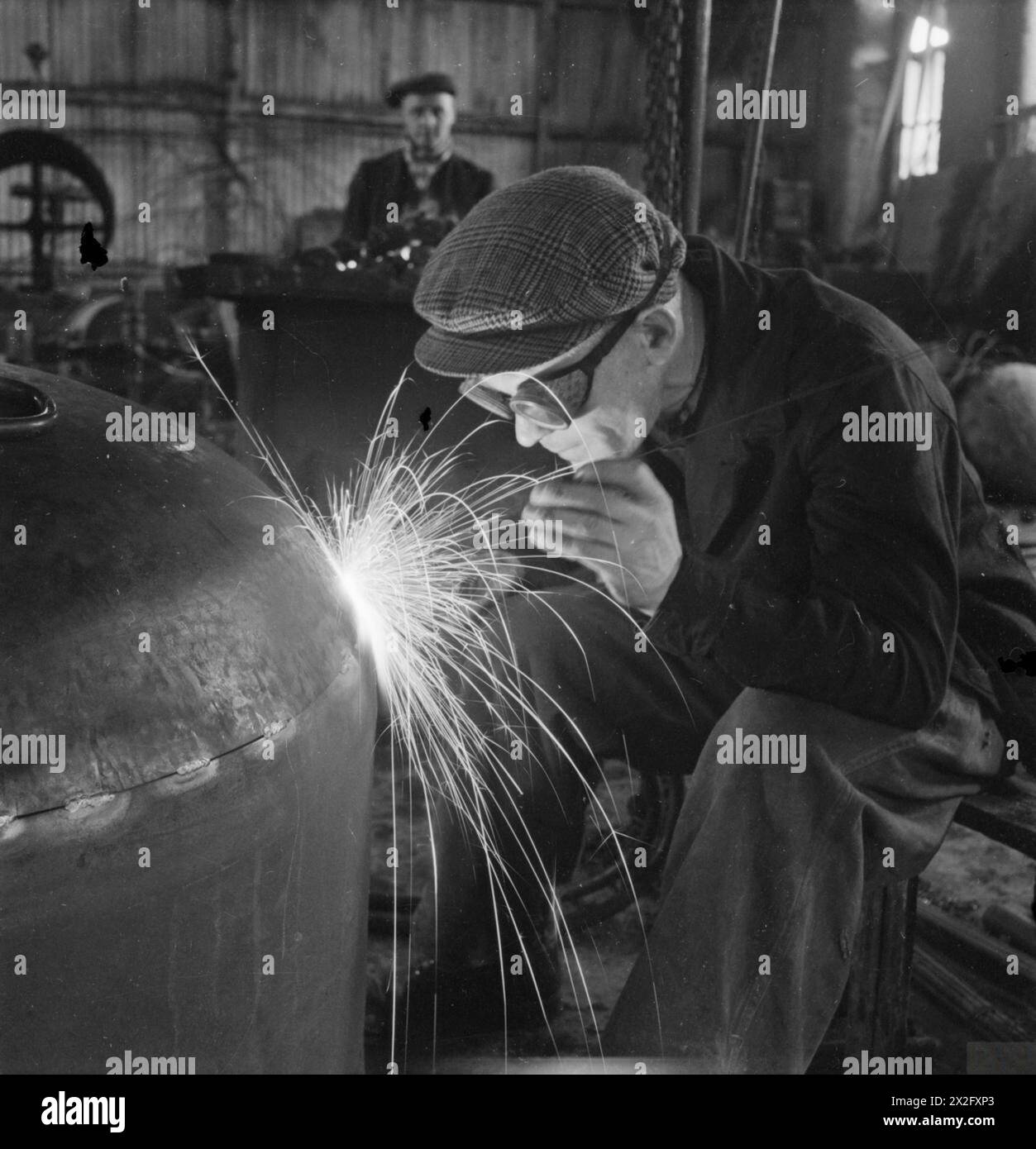 Un artigiano salda la parte superiore di un involucro a cupola in una fabbrica di locomotive britannica nel 1945, durante la produzione di locomotive ferroviarie nel Regno Unito. Foto Stock
