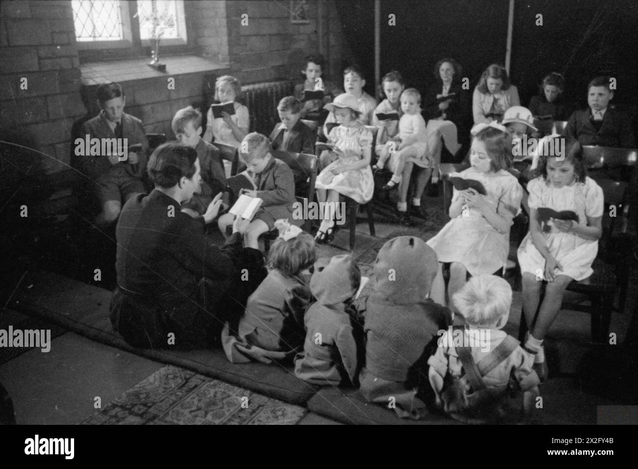 Nel 1944, il reverendo Joseph Stephens condusse i bambini di età compresa tra i 2 e i 14 anni in attività di inni presso la Sunday School nella St Mark's Church, Silvertown, Londra. A causa dei danni causati dalla guerra, le sessioni si sono svolte in una sezione chiusa, con visite estive allo zoo di Chessington e viaggi invernali a una pantomima londinese finanziata da raffles e donazioni. Foto Stock