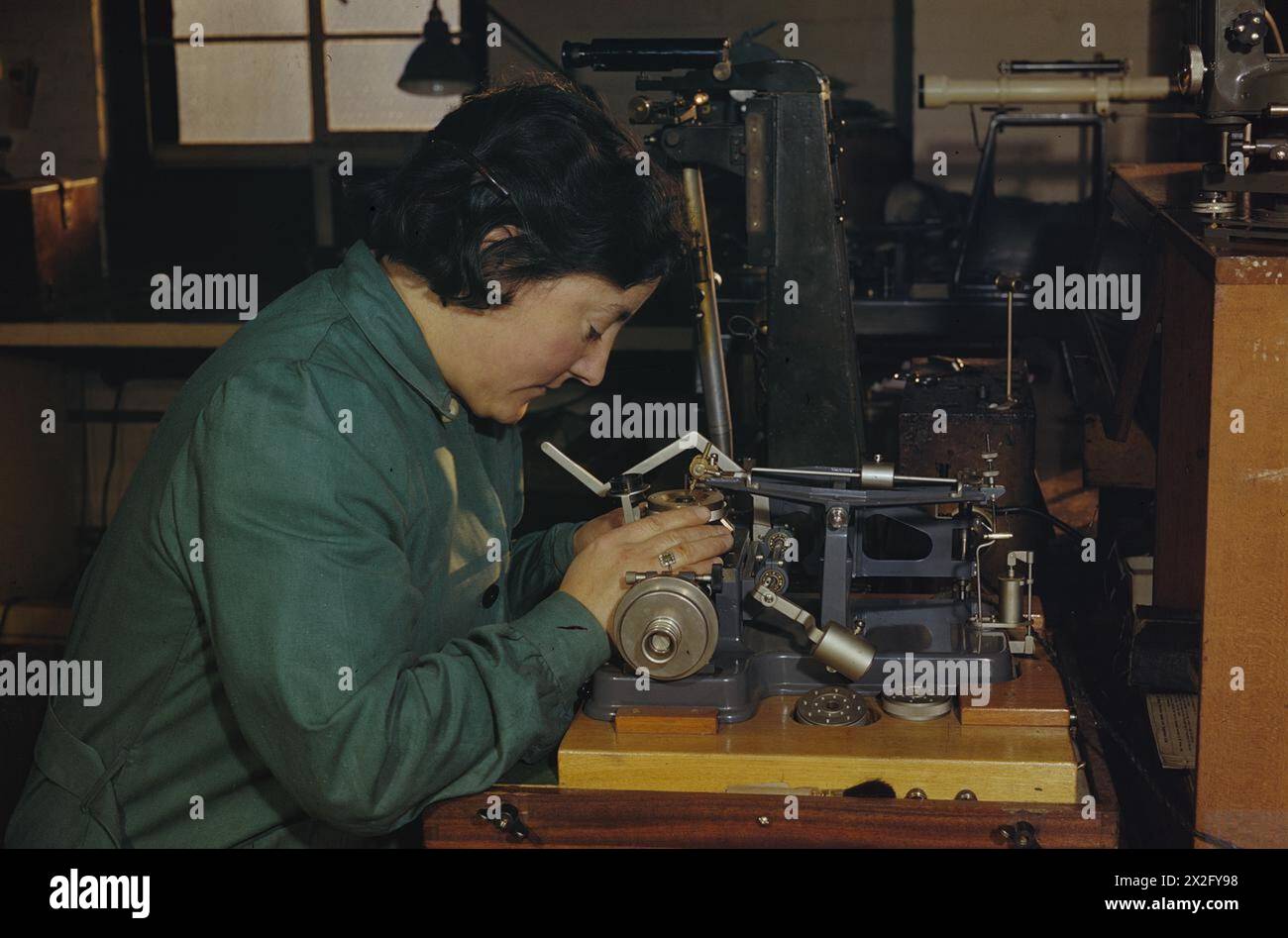 DONNE OPERAIE DI GUERRA IN GRAN BRETAGNA, 1945 - in una fabbrica a Camberwell, Londra, abili artigiani realizzano strumenti di precisione. Una donna operaia di guerra imposta una macchina per tagliare il reticolo di uno strumento di misurazione di precisione Foto Stock