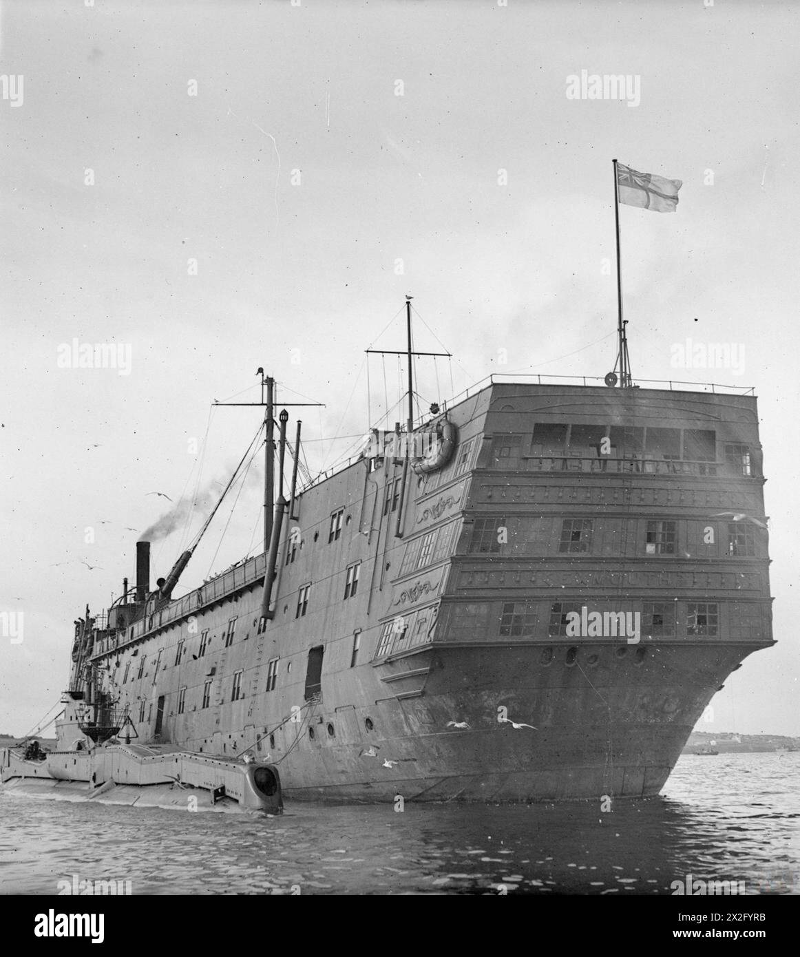 IL LAVORO DI GUERRA DI EXMOUTH COME NAVE MINESWEEPER DEPOT. 29 SETTEMBRE 1943, SCAPA FLOW. COME NAVE DEPOT SI OCCUPA DEL BENESSERE, DELLA RICREAZIONE E DELL'ADDESTRAMENTO DEGLI EQUIPAGGI DELLE MINESWEEPERS E DEGLI EQUIPAGGI DEI SOTTOMARINI. - HMS EXMOUTH con il TONNO sommergibile a fianco della Royal Navy, HMS Exmouth, Destroyer, (1934) Foto Stock