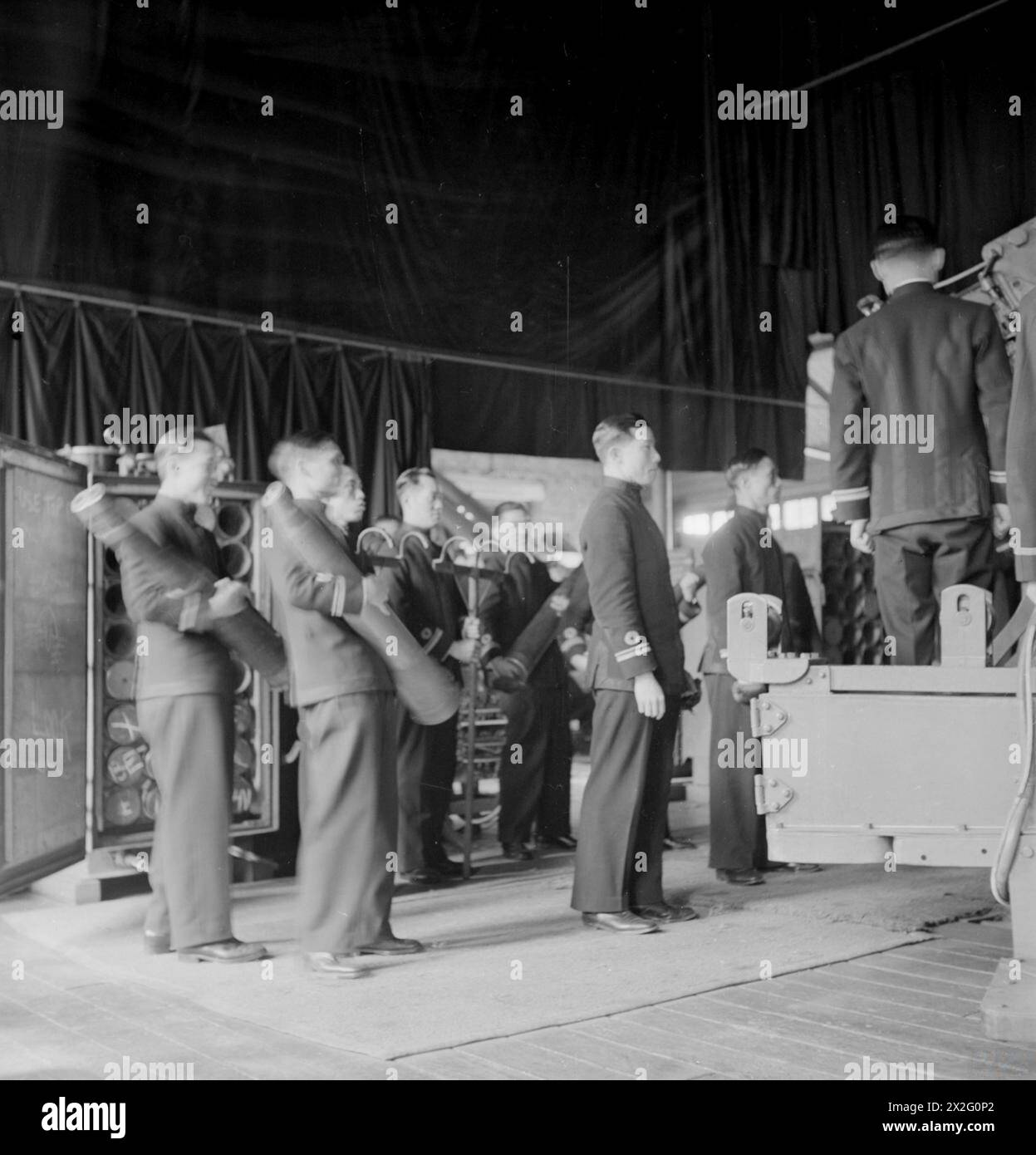 Gli ufficiali cinesi ricevono istruzioni sul caricamento di un cannone gemello da 4 pollici presso la Chatham Gunnery School in Inghilterra nell'agosto 1945 come parte dell'addestramento della Royal Navy. Foto Stock