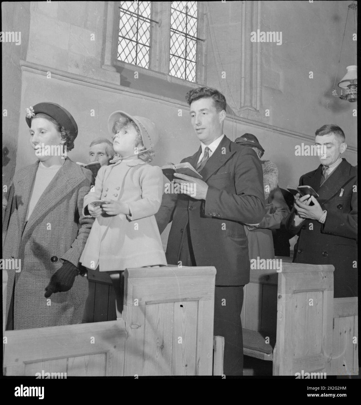 VILLAGE CHURCH: VITA QUOTIDIANA A UFFINGTON, BERKSHIRE, INGHILTERRA, Regno Unito, 1944 - i membri della congregazione si uniscono per cantare un inno durante Evensong nella Chiesa di Santa Maria Vergine, Uffington, Berkshire Foto Stock