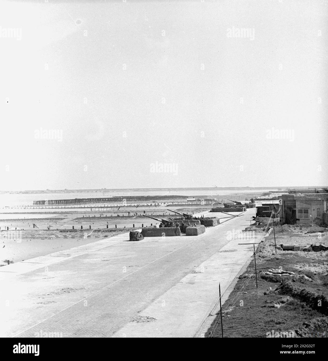 I ROYAL MARINES SONO TORNATI A ZEEBRUGGE. APRILE 1945, ZEEBRUGGE, BELGIO. I ROYAL MARINES DI UN FAMOSO REGGIMENTO ANTIAEREO CHE HANNO STABILITO LE LORO POSIZIONI IN VISTA DELLA TALPA ZEEBRUGGE. Posizione dei Royal Marines con la Mole sullo sfondo Foto Stock