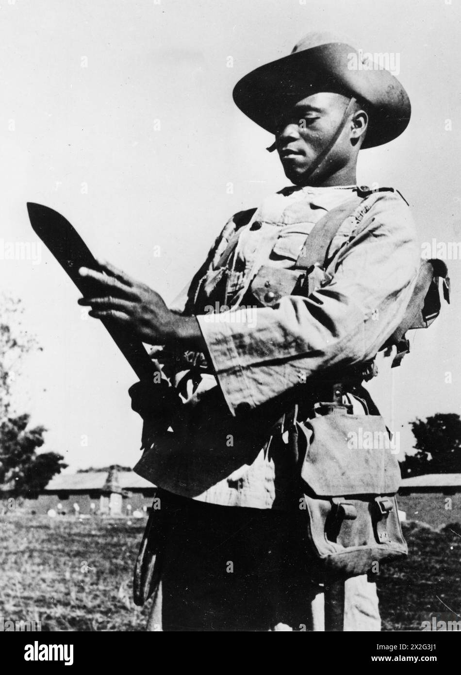Un soldato King's African Rifles a Nyasaland gestisce un panga, utilizzato per il lavoro da campo, per la pulizia della vegetazione, per fare difese e per autodifesa, dal 10 al 18 aprile 1941. Foto Stock