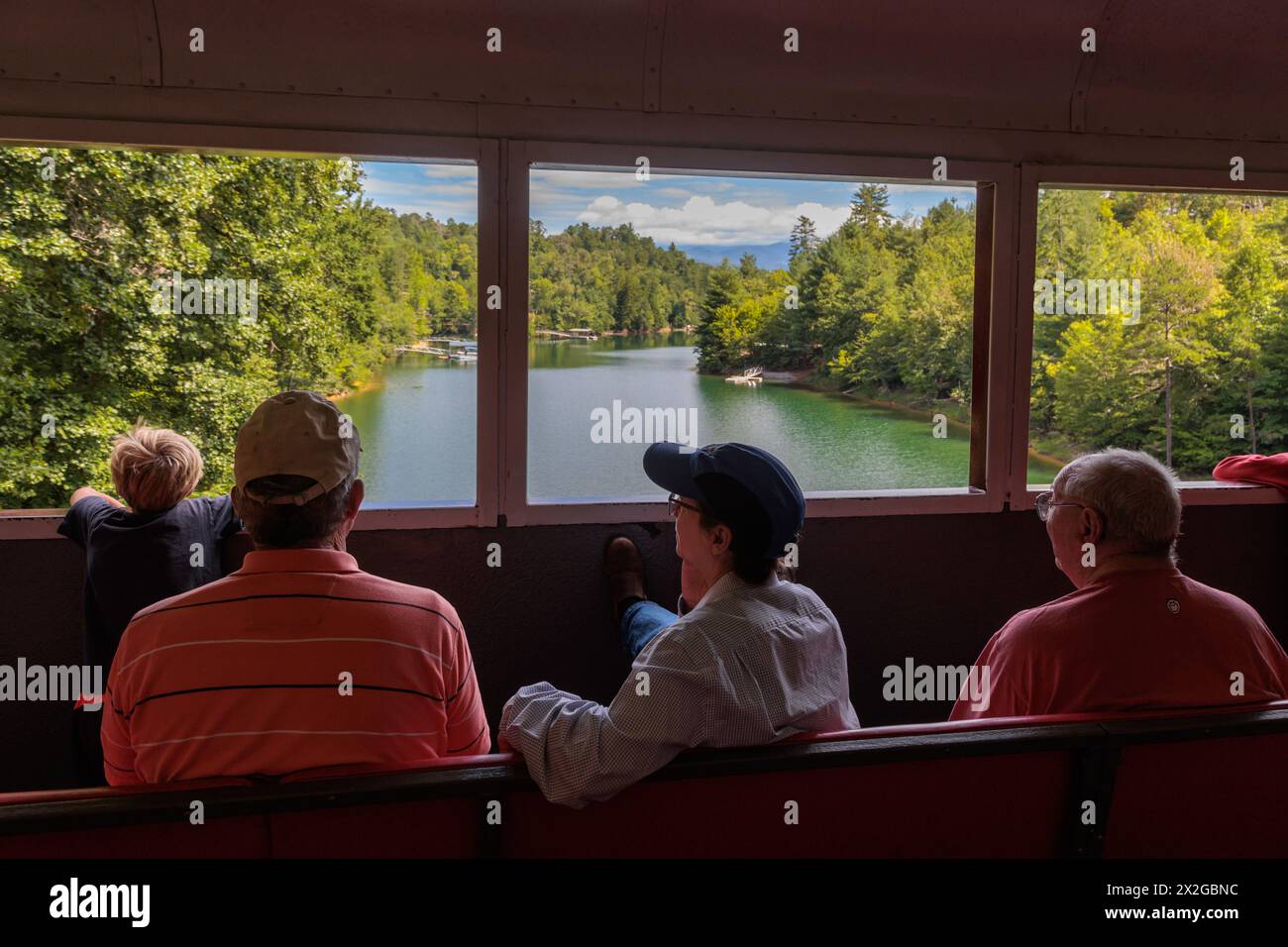 I passeggeri della Great Smoky Mountains Railroad che guardano fuori dai finestrini del vagone ferroviario scoperto durante un'escursione da Bryson City, North Carolina Foto Stock