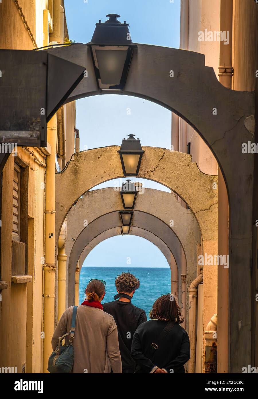 Persone che camminano attraverso strade strette con portici verso il mare Foto Stock