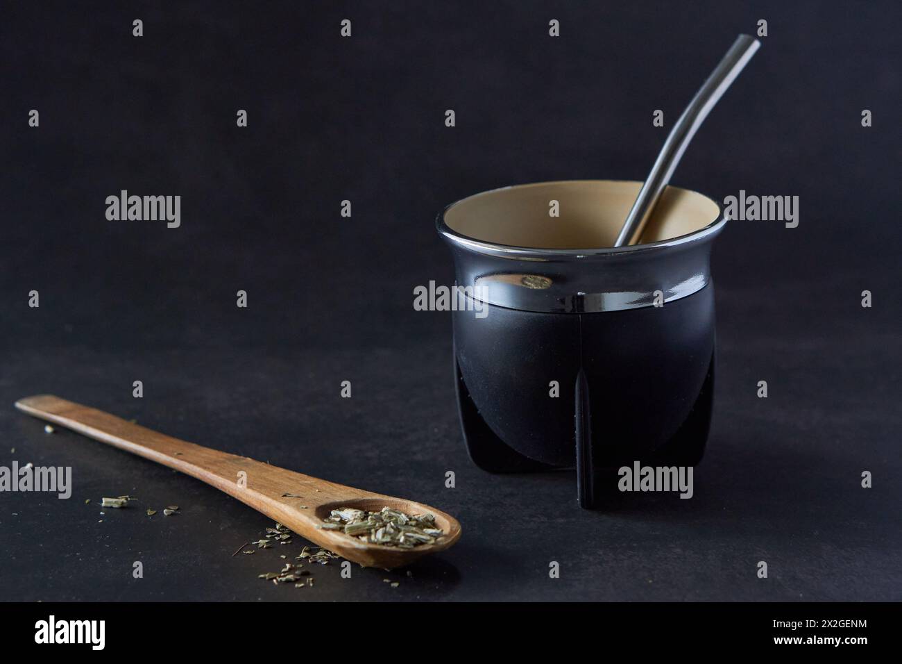black mate con bombilla su sfondo nero e un cucchiaio di legno con yerba mate. copia spazio. tradizionale bevanda calda argentina Foto Stock