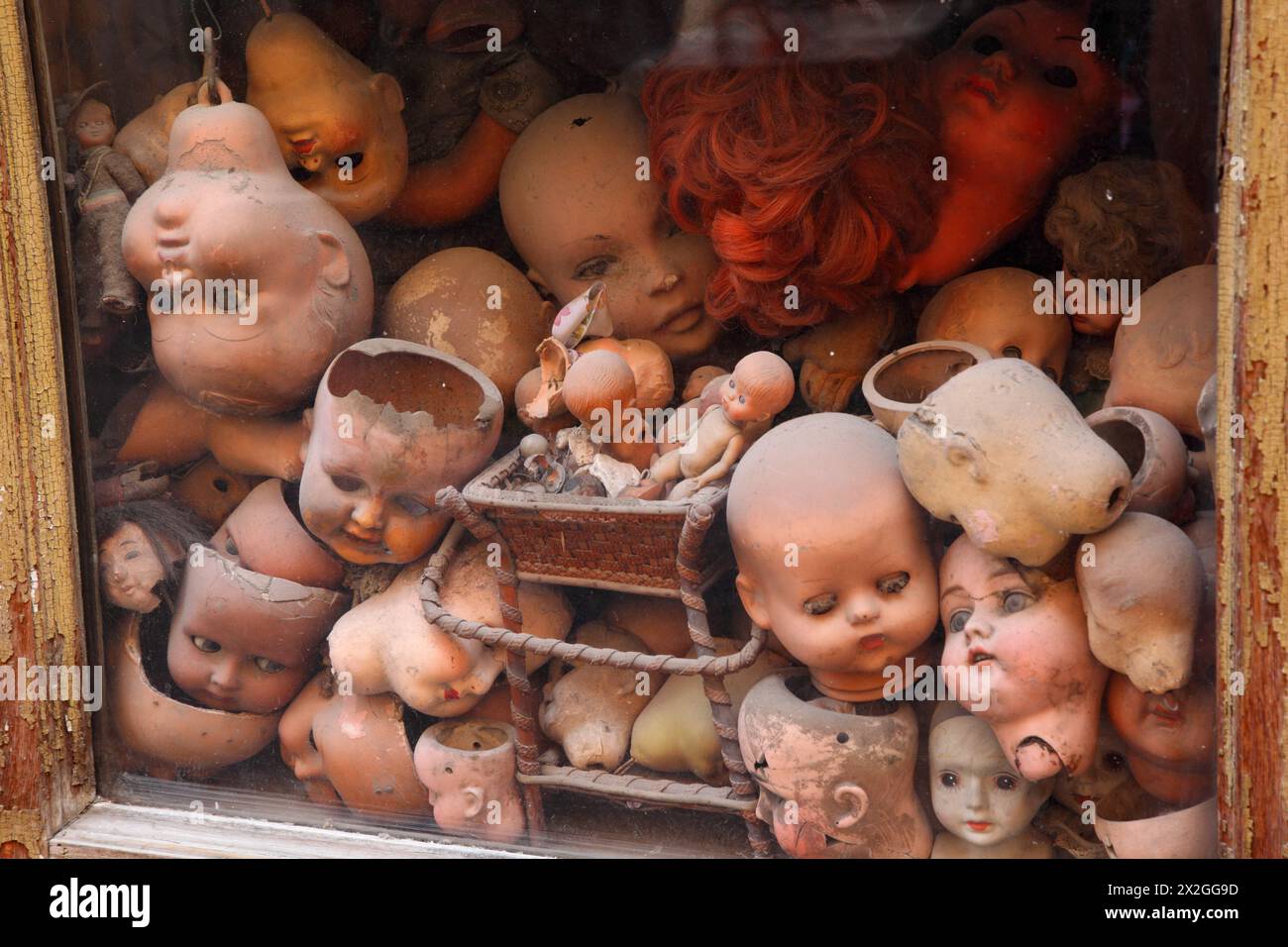 vecchia vetrina con molte vecchie bambole testa, capelli di bambola rossa, diverse piccole bambole Foto Stock