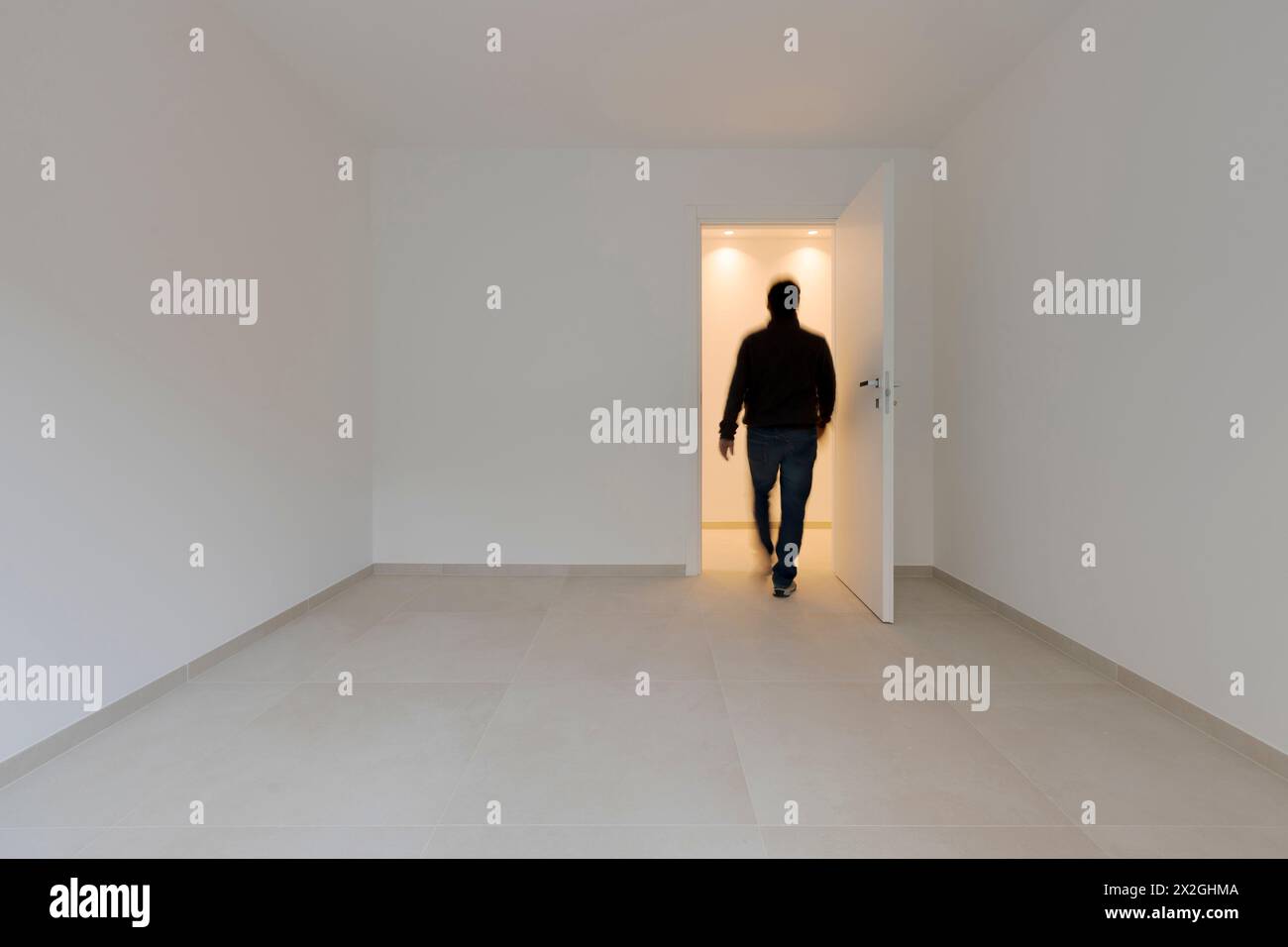 Un uomo in una stanza vuota esce e viene visto da dietro muoversi. Immagini concettuali. Si tratta di un adulto che cammina verso l'uscita, Foto Stock
