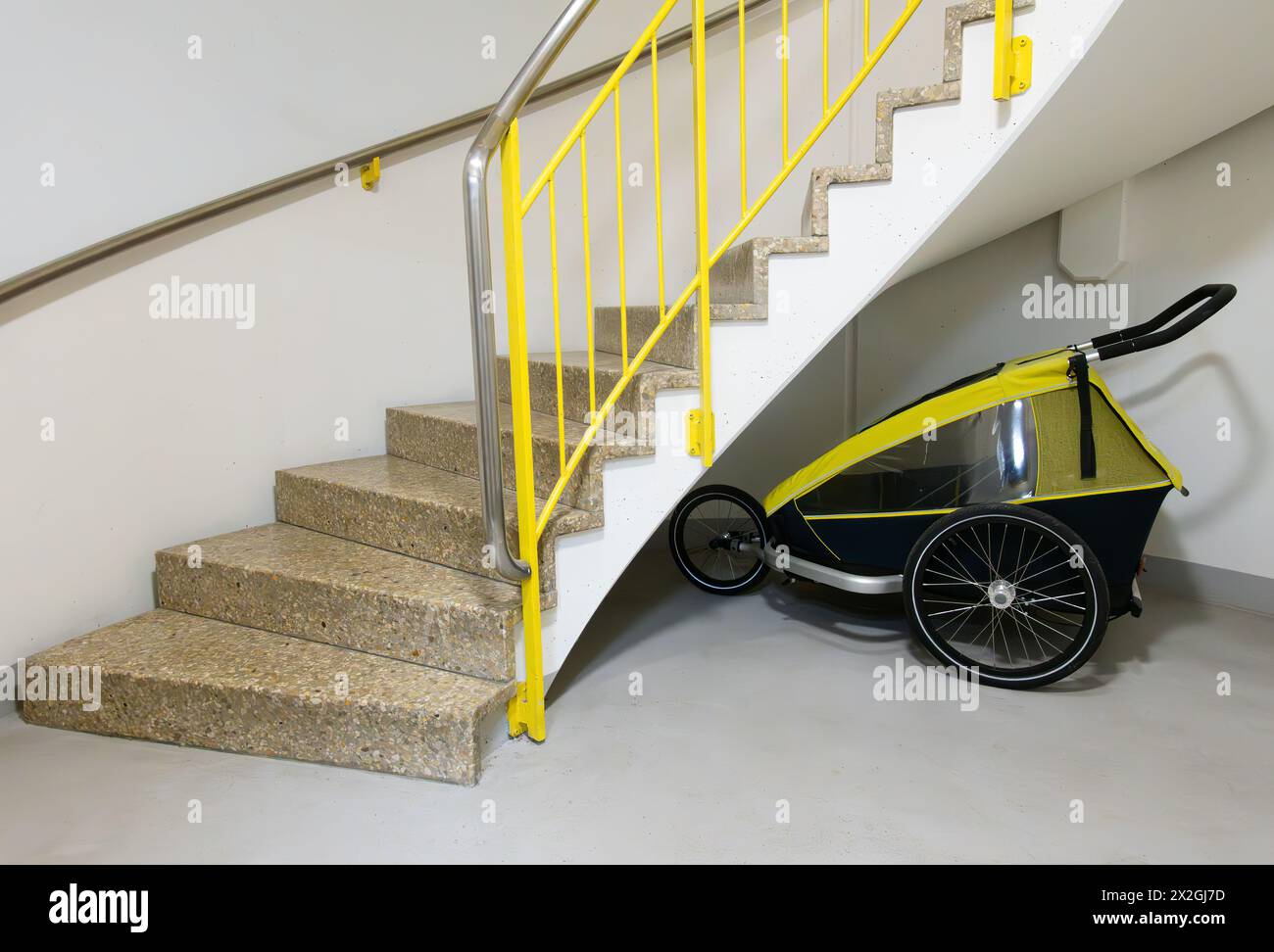 Rimorchio per biciclette per bambini parcheggiato sotto le scale di un condominio Foto Stock