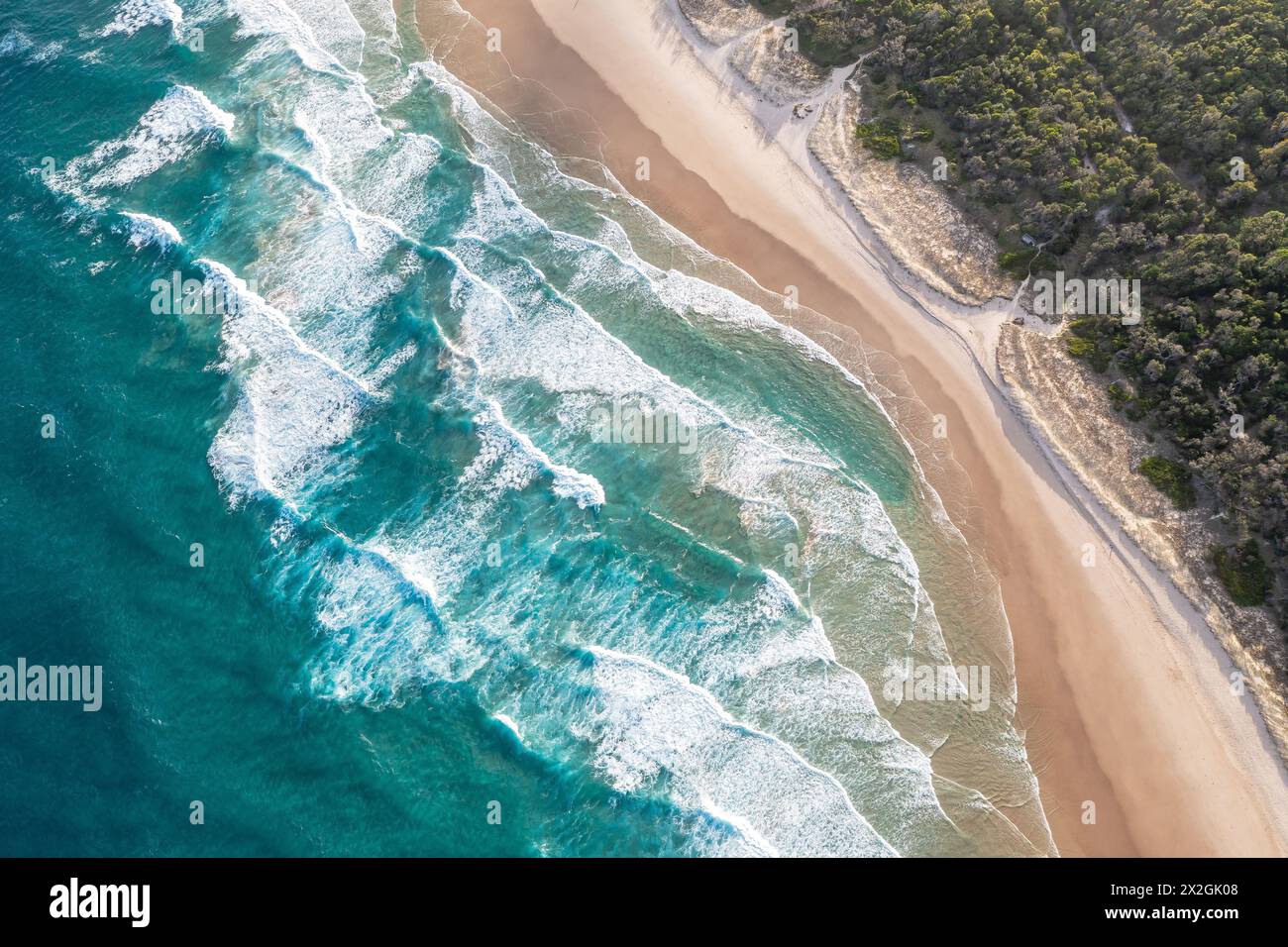 Le onde spumeggianti dell'oceano si avvolgono e si avvicinano alla spiaggia sabbiosa. Maestà, paesaggio marino turchese. Vista dall'alto dal drone. Foto Stock