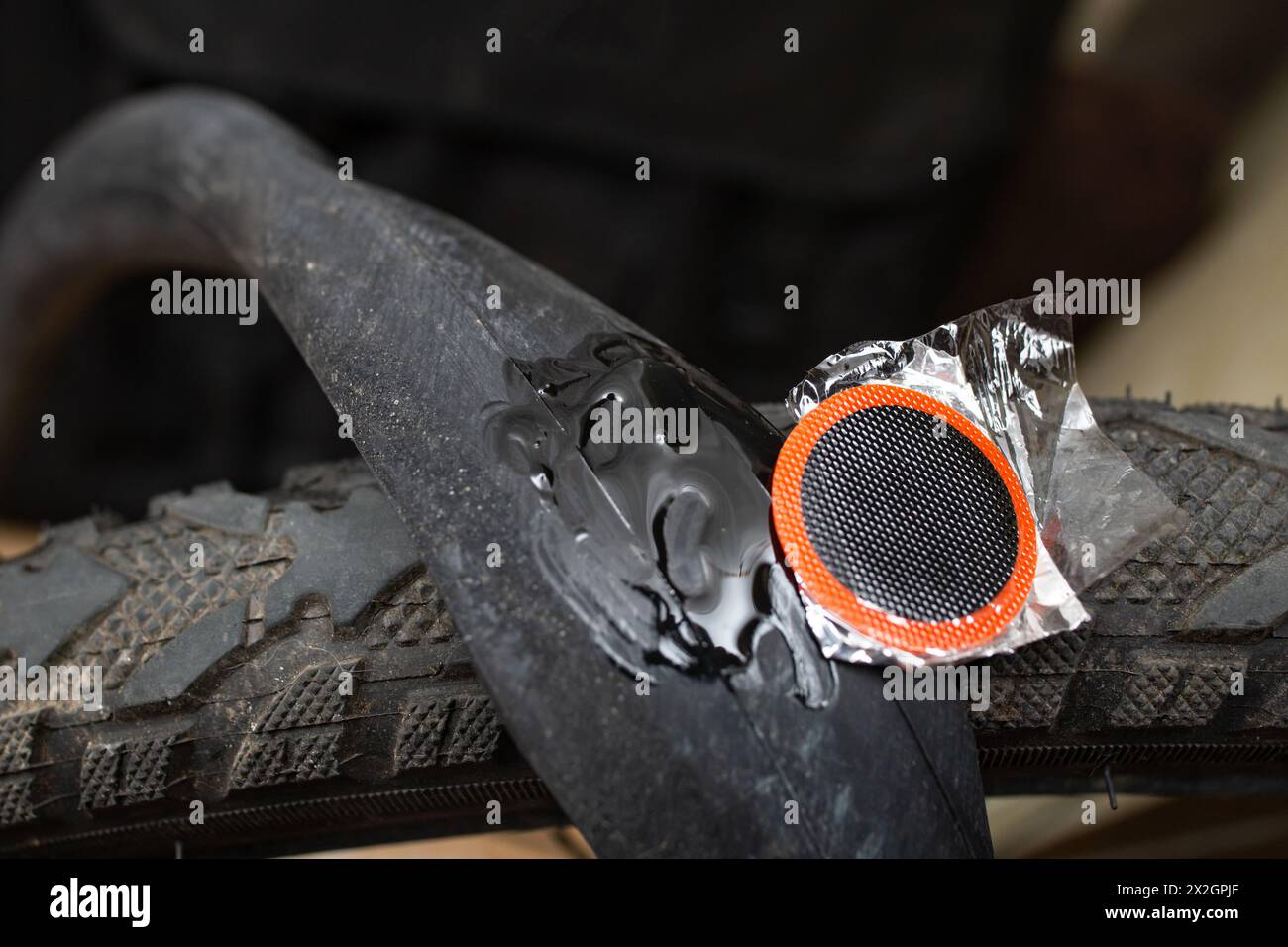 Applicazione di una patch a una fotocamera in gomma con ruota per bicicletta con colla, messa a fuoco morbida in primo piano Foto Stock