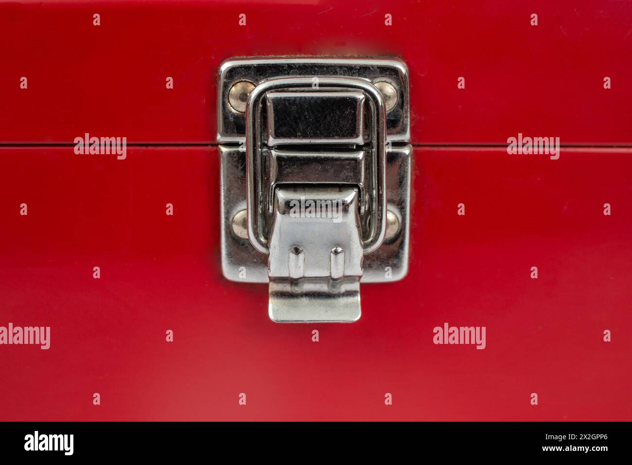 Blocco a scatto in acciaio inox su una custodia metallica rossa, coperchio chiuso di una scatola verniciata di rosso Foto Stock