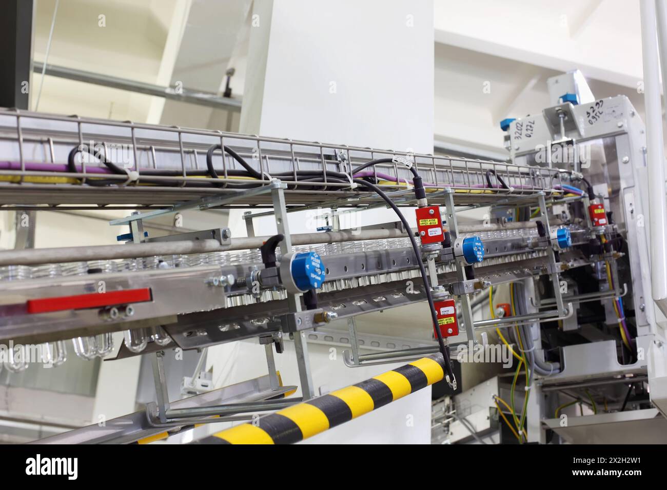 Trasportatore con preforme in plastica per la produzione di bottiglie in PET nel reparto della grande fabbrica Foto Stock