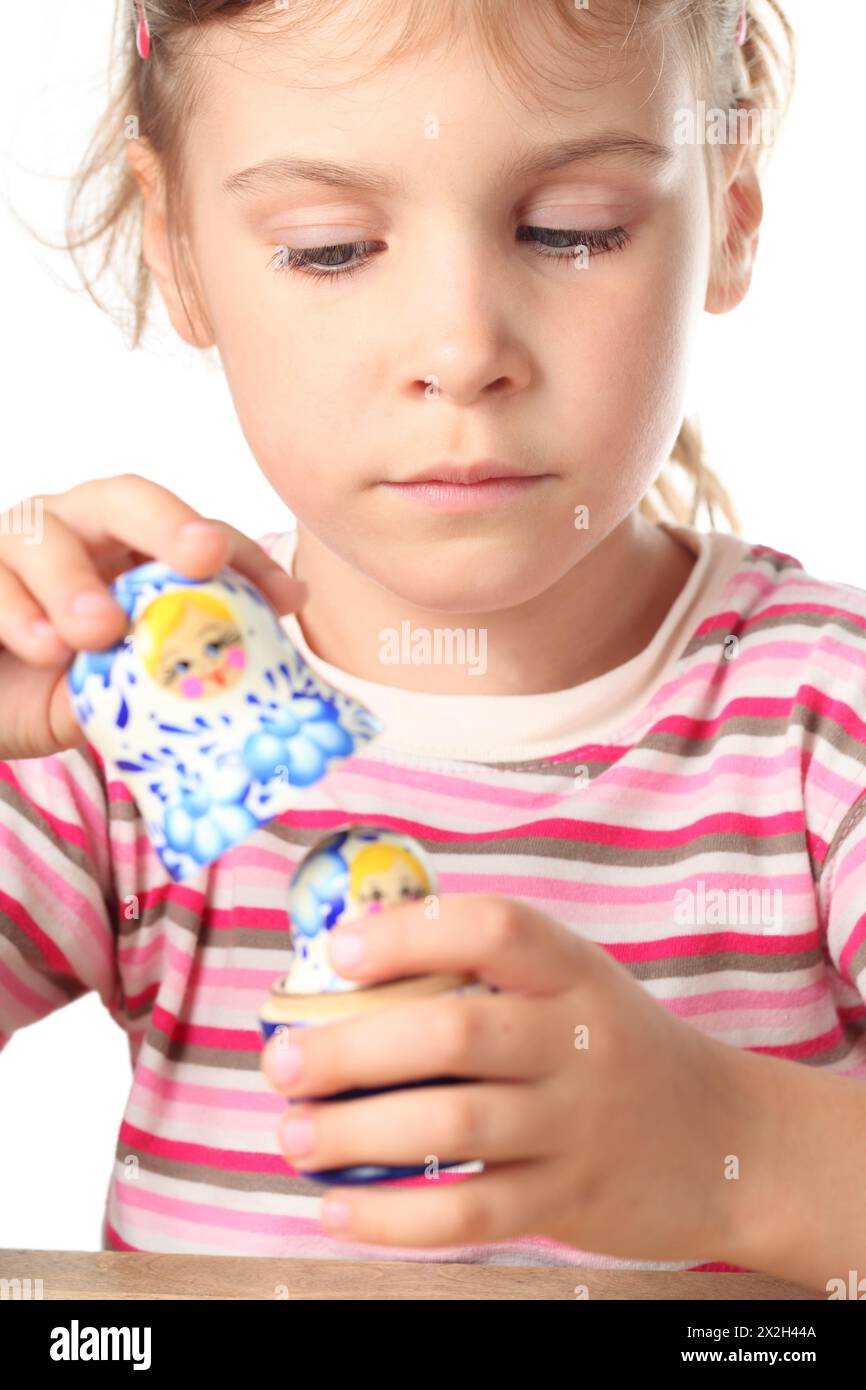 la bella bambina mantiene blu matryoshka isolato su bianco Foto Stock