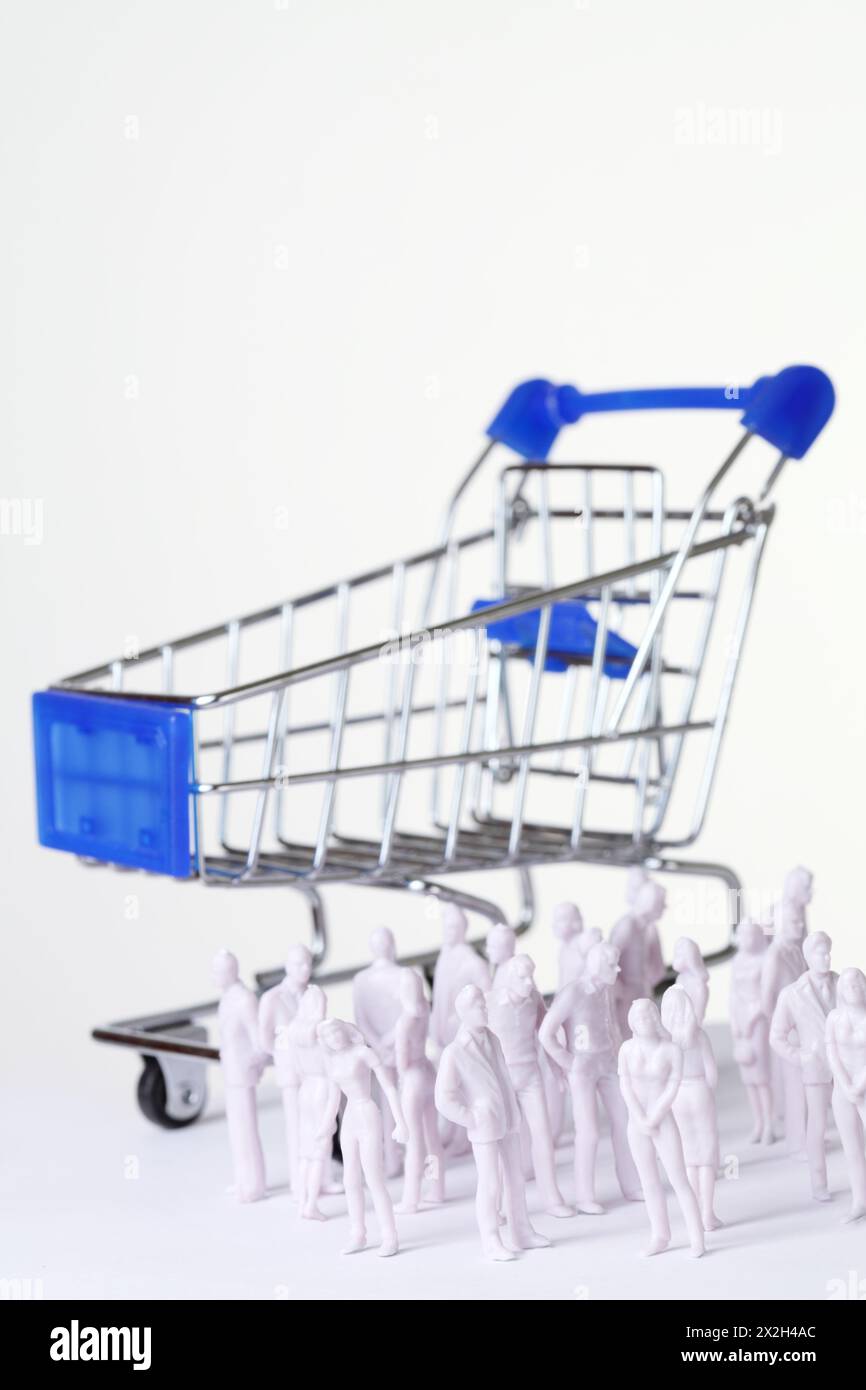le persone in miniatura bianche si trovano in posizioni diverse vicino al grande carrello della spesa Foto Stock