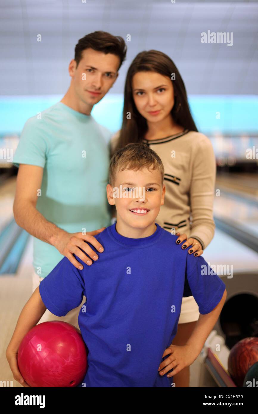 Giovane padre e madre con figlio nel club di bowling; concentrarsi sul ragazzo; bassa profondità di campo Foto Stock