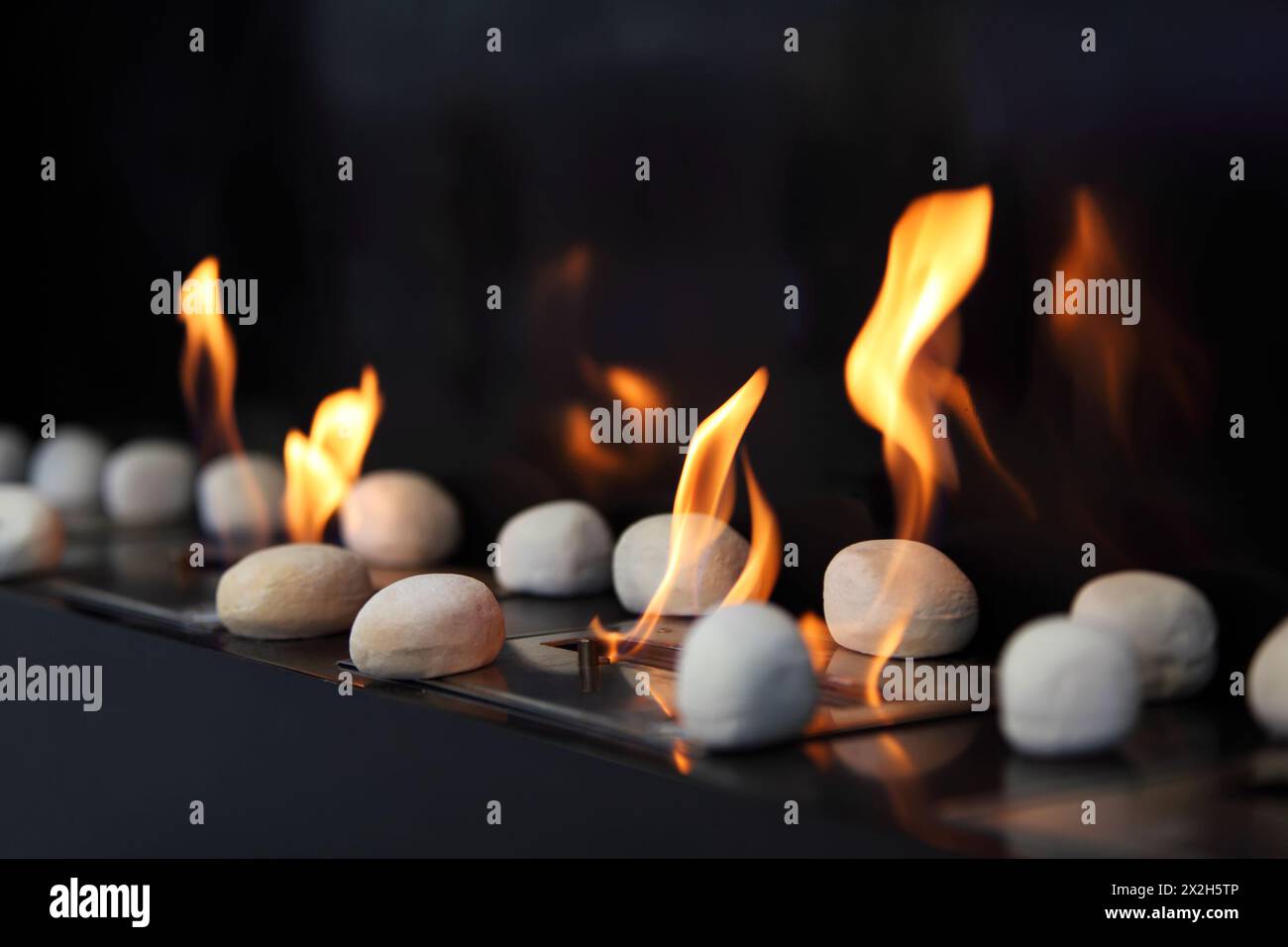 Pietre circolari bianche e bellissime fiamme gialle nel caminetto Foto Stock
