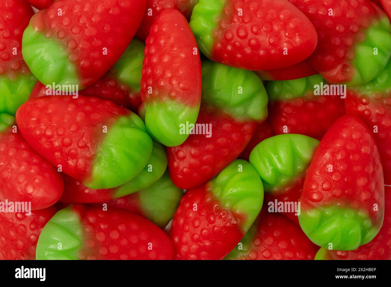 Caramelle di gelatina e fragole isolate su sfondo bianco. Vista dall'alto. Deliziose caramelle di gelatina. Foto Stock