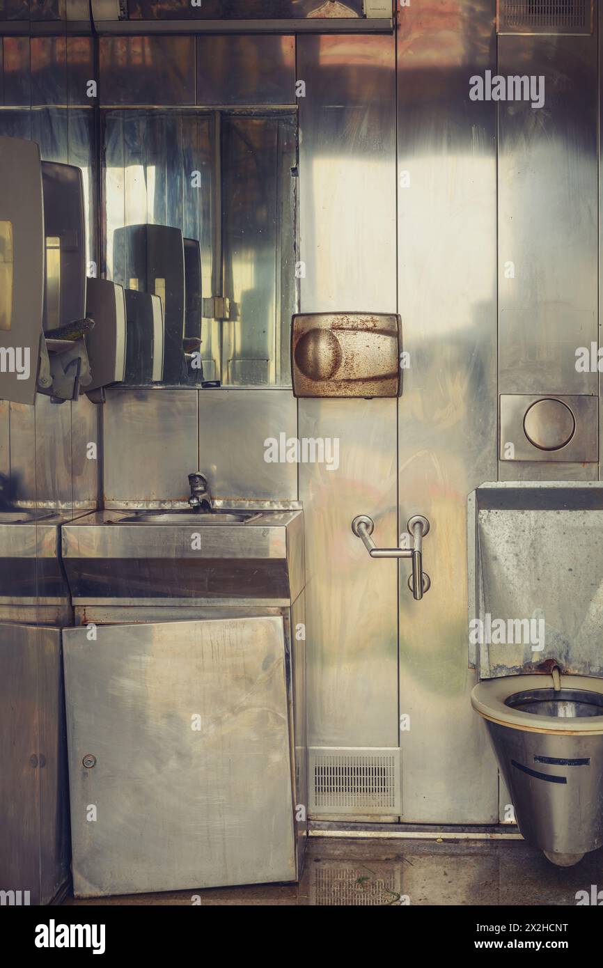Vecchio bagno pubblico sporco con interni metallici, immagine verticale Foto Stock