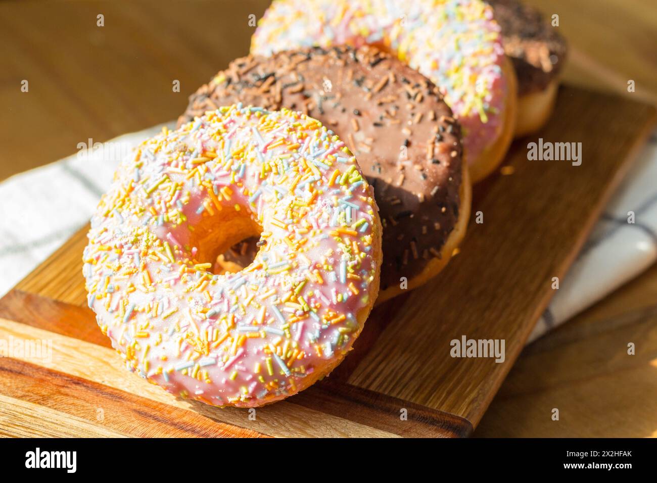 Ciambelle ad anello ghiacciate su tavola di legno Foto Stock