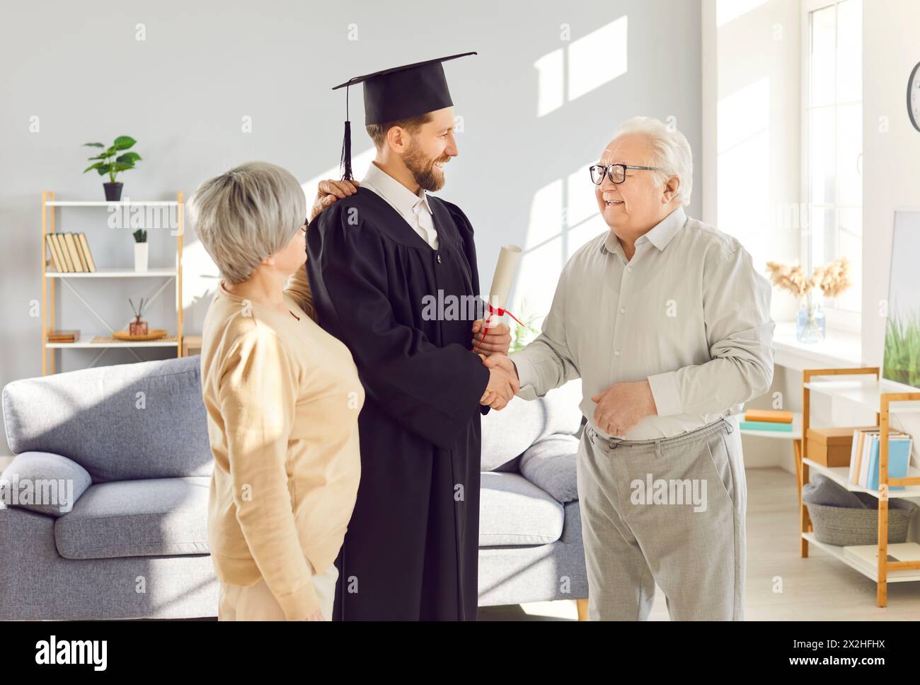 Padre e madre anziani che si congratulano con il figlio, studente laureato Foto Stock