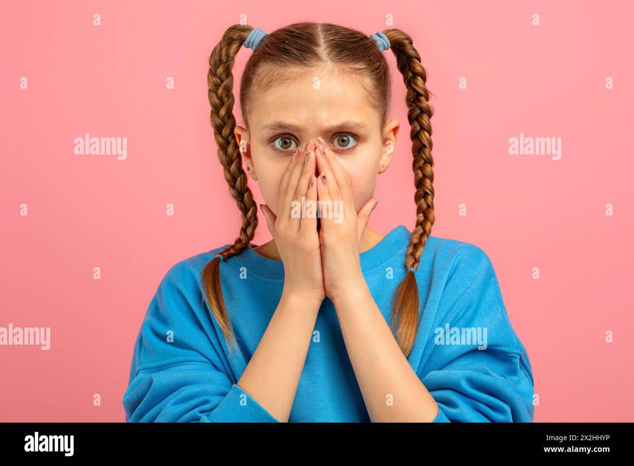 Sorpresa adolescente che copre la bocca con le mani su sfondo rosa Foto Stock