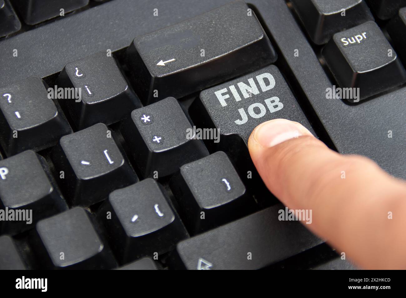 Primo piano di un dito premendo il tasto di ricerca lavoro sulla tastiera di un laptop Foto Stock