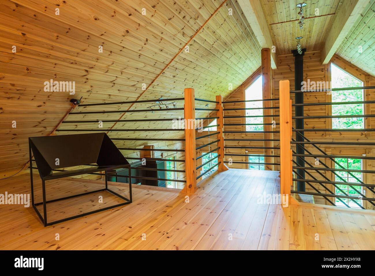 Sedia da seduta in metallo nero e ringhiere tubolari con pali in legno in un ufficio domestico su soppalco all'interno di una casa in legno di pino scozzese pezzo sur Piece Foto Stock