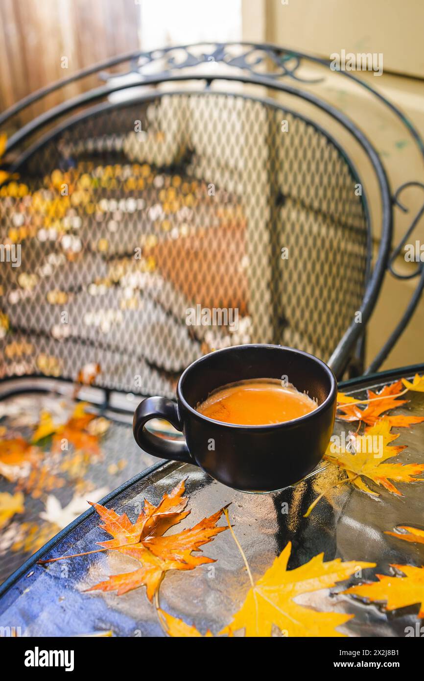 Tazza di caffè sul tavolo del patio con foglie gialle Foto Stock